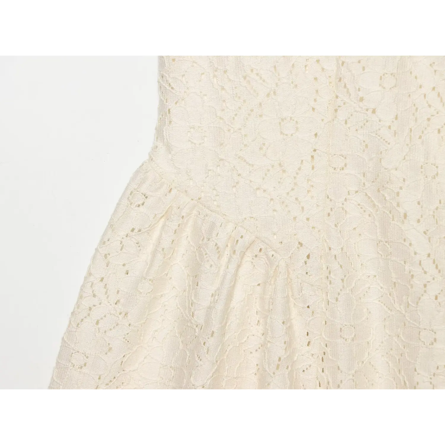 Close‑up of cream lace mini dress waist seam, showing skirt gathering and floral lace fabric texture