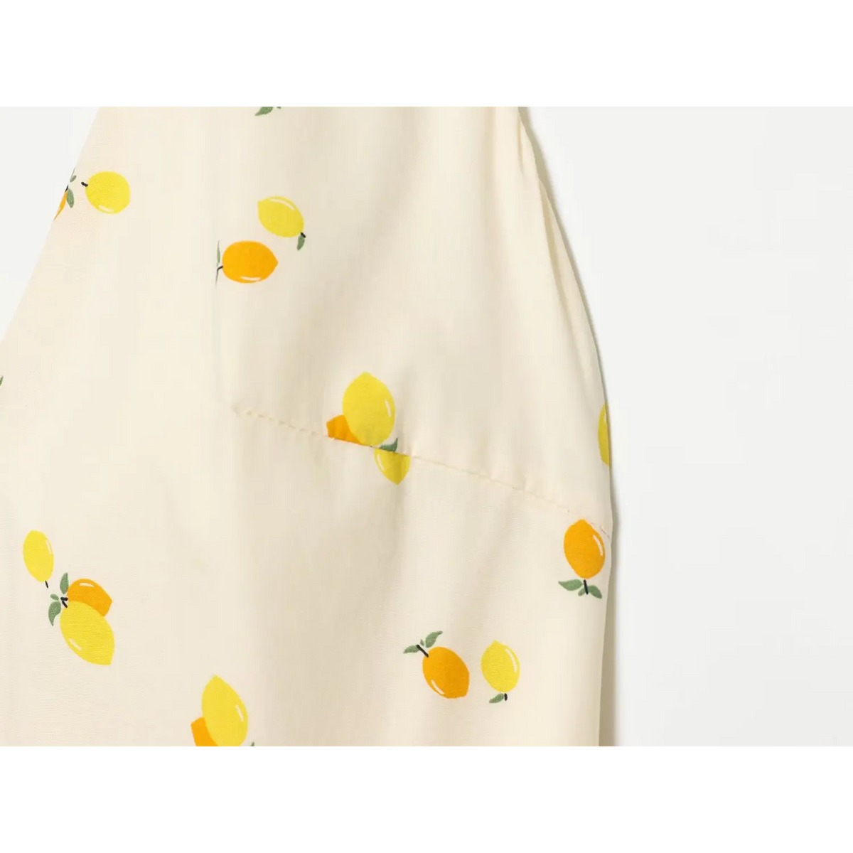 Macro close‑up of cream fabric with yellow lemon fruit print