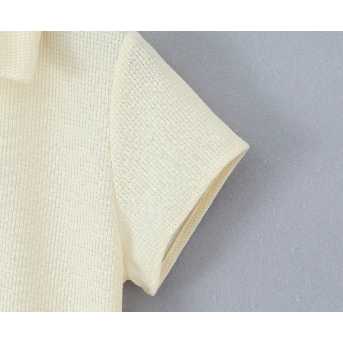 Close‑up of short sleeve cuff and waffle knit fabric of cream polo mini dress
