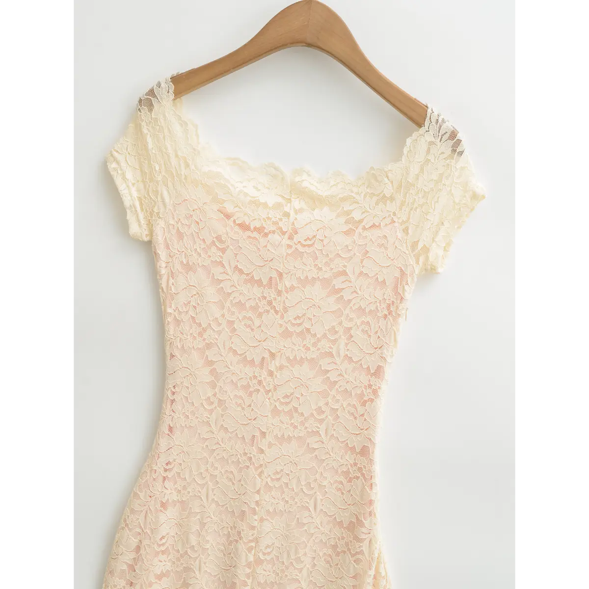 Full view of cream off‑the‑shoulder short sleeve lace dress hung on wooden hanger