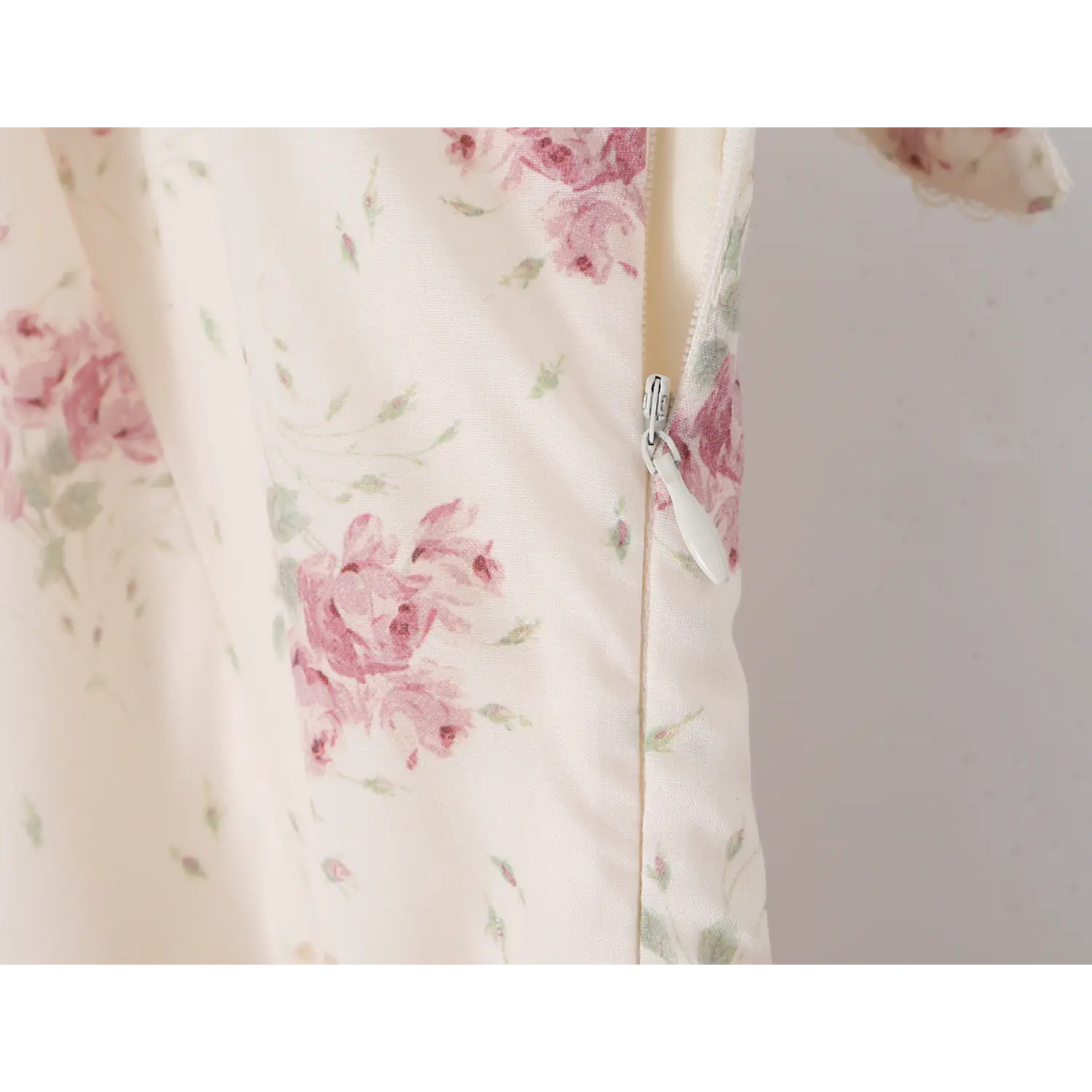 Partial close‑up of invisible side zipper on cream floral mermaid dress