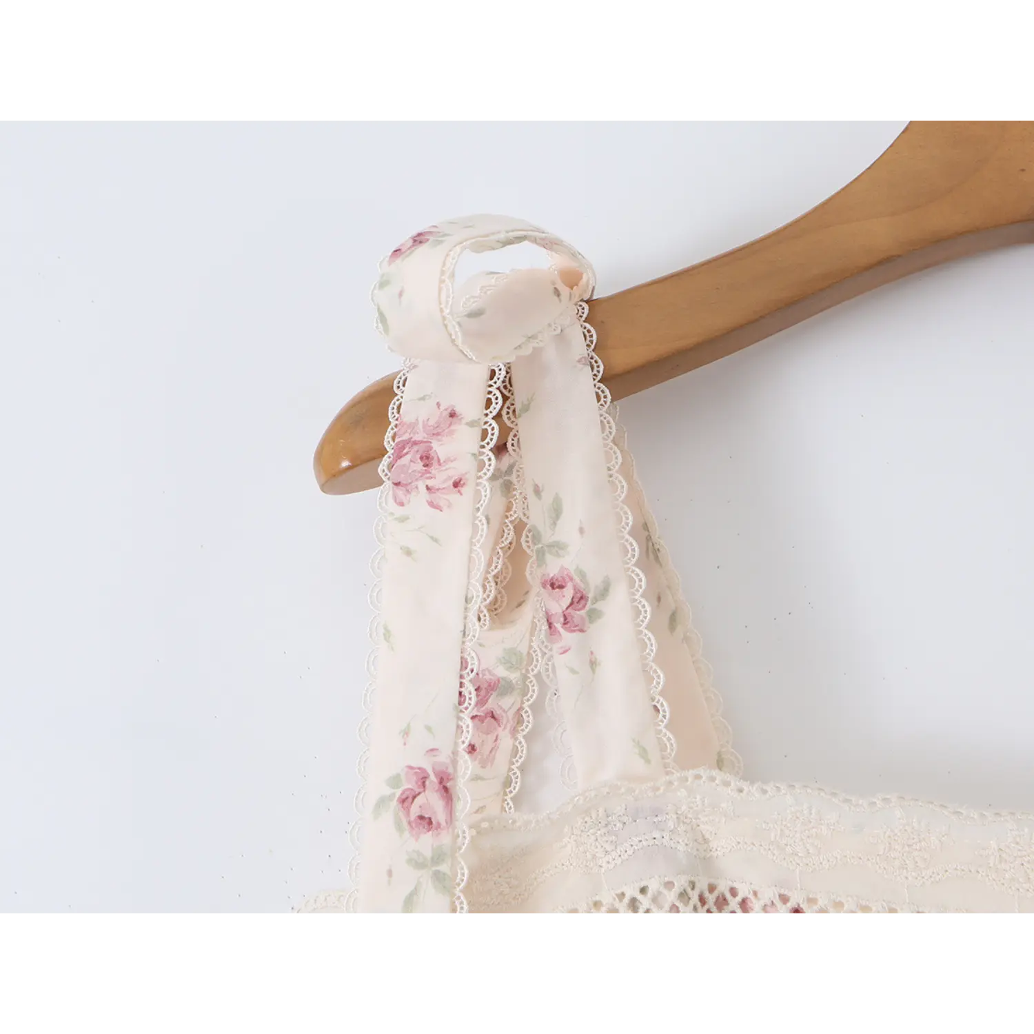 Close‑up of fabric tie shoulder strap detail on cream floral maxi dress