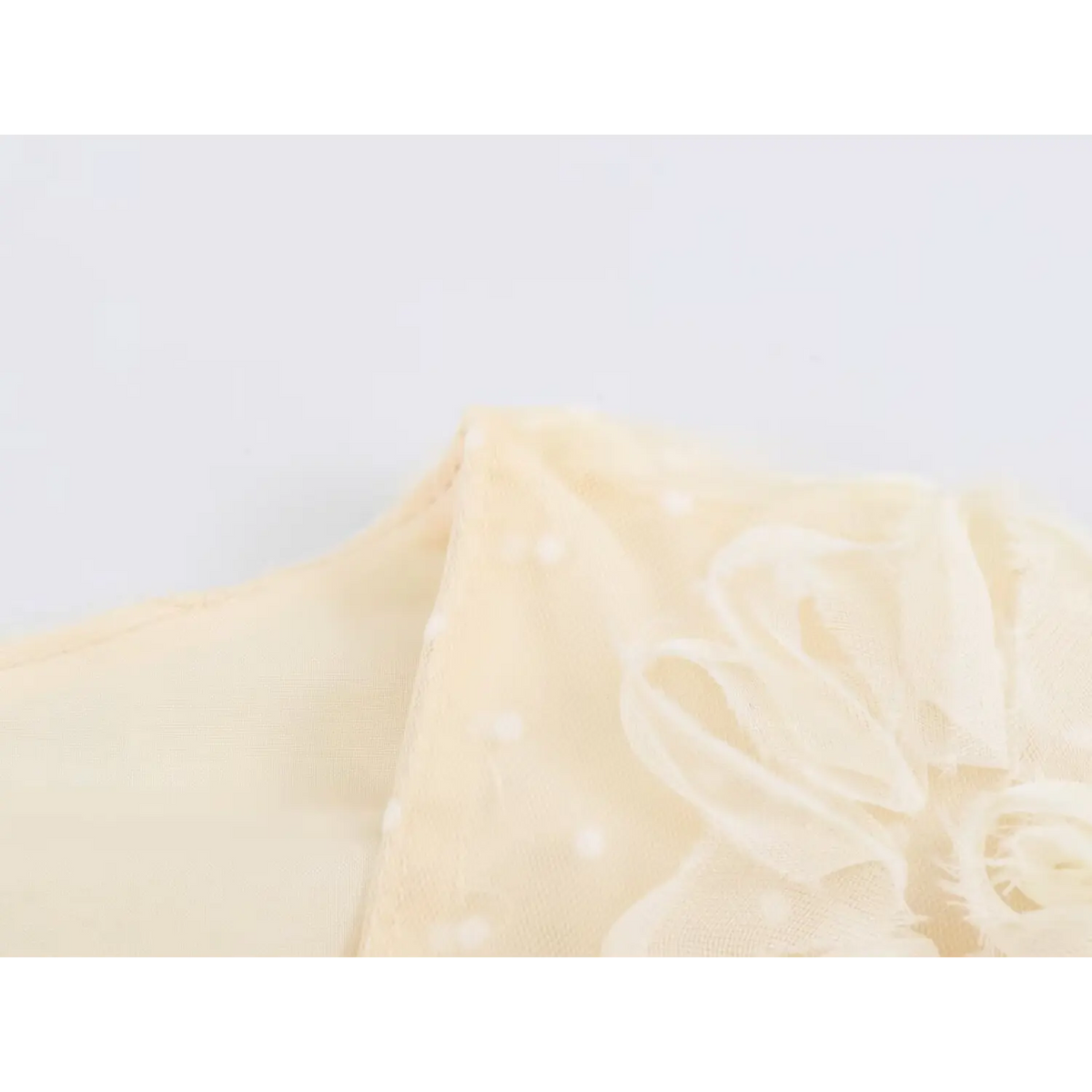 Close‑up of flutter sleeve hem with 3d floral trim on cream tulle maxi dress