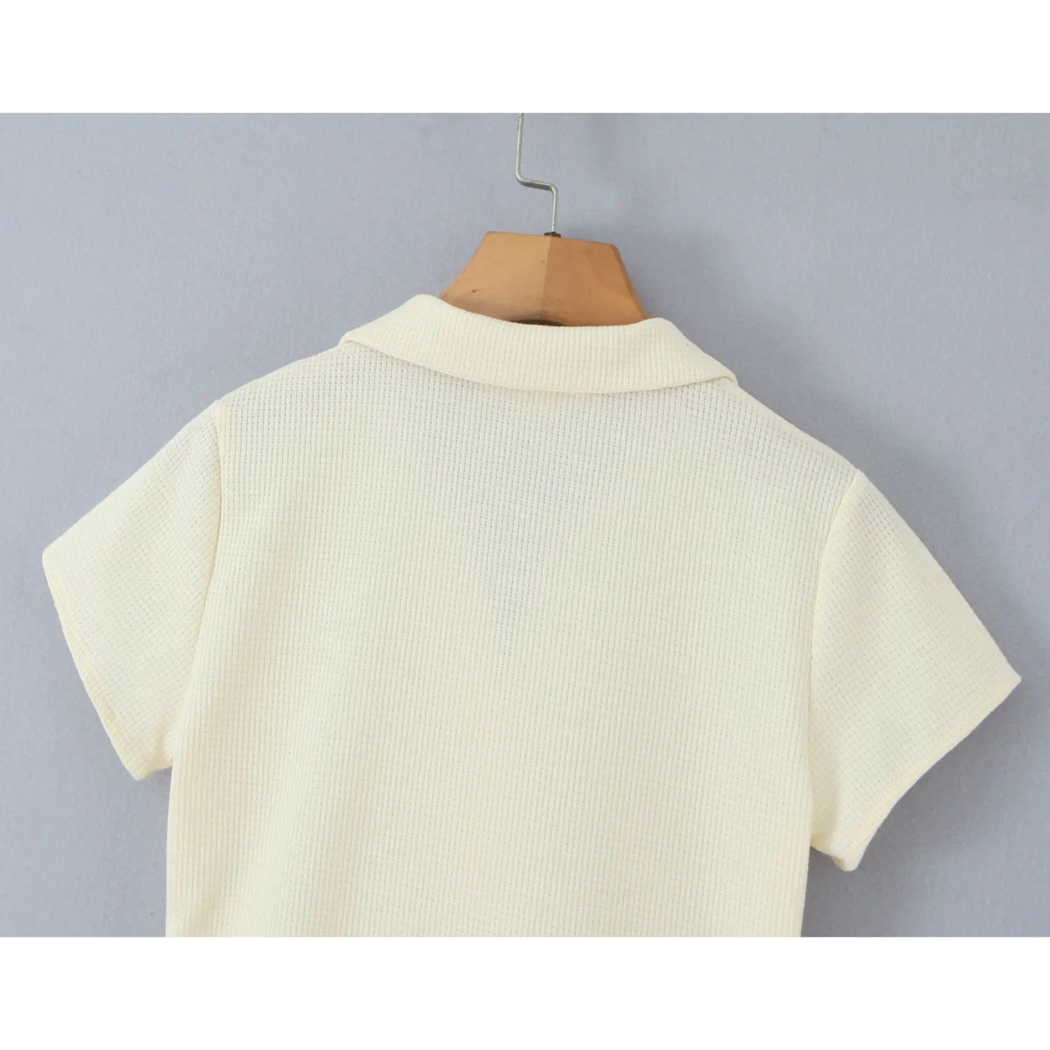 Back view close‑up of cream waffle knit polo dress, collar and short sleeve on wooden hanger