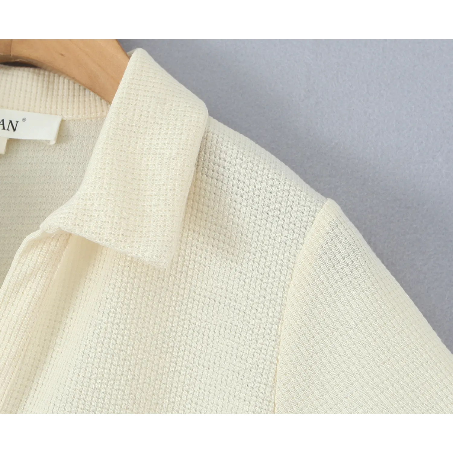 Macro close‑up of polo collar and waffle knit fabric texture on cream short sleeve dress