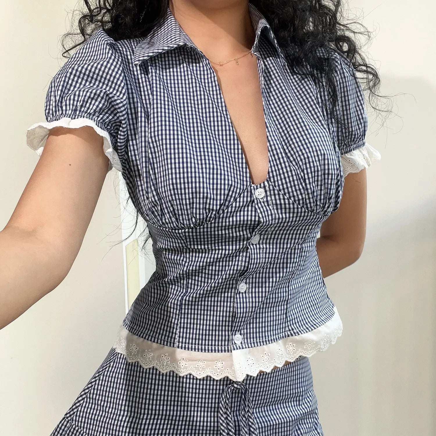 Crop gingham top close-up front model detail shot, clear pointed V lapel vertical bust gathering shaping puff elastic short sleeves wavy eyelet lace cuffs slim cropped silhouette highlight waistline detail shot