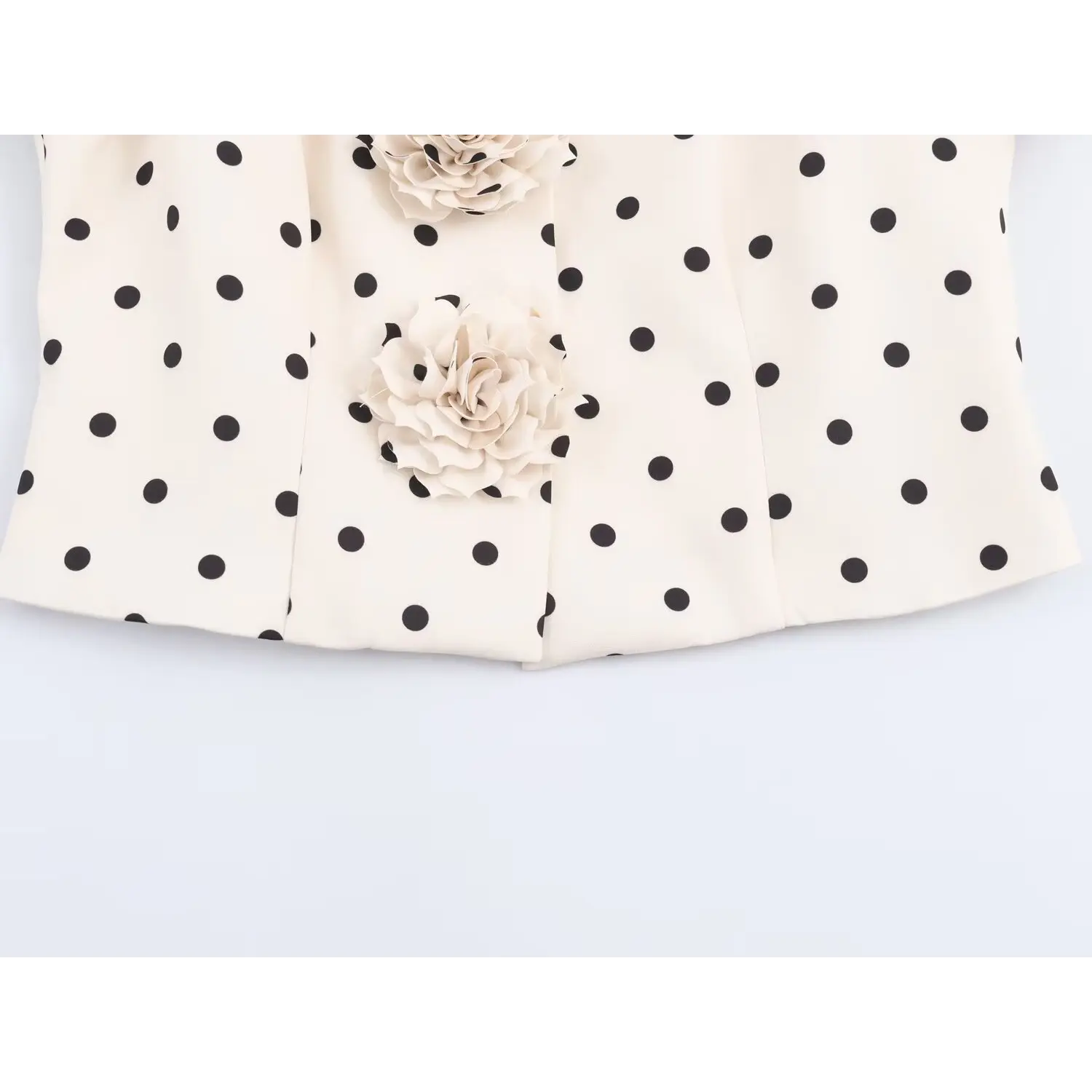 Waist hem close-up of white polka dot cropped jacket with attached fabric rose ornaments