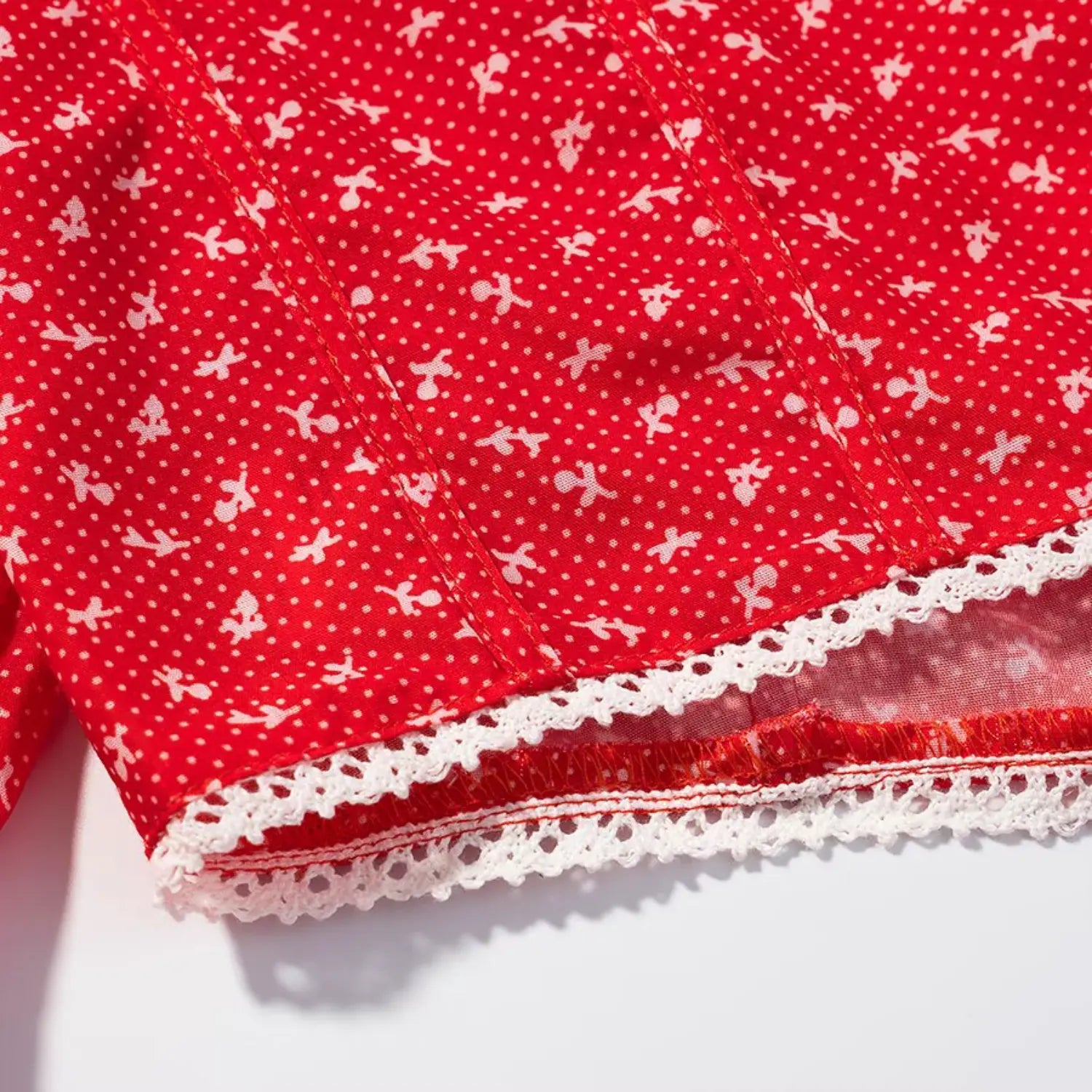 Close‑up of white lace trim hem on red ditsy floral cropped blouse