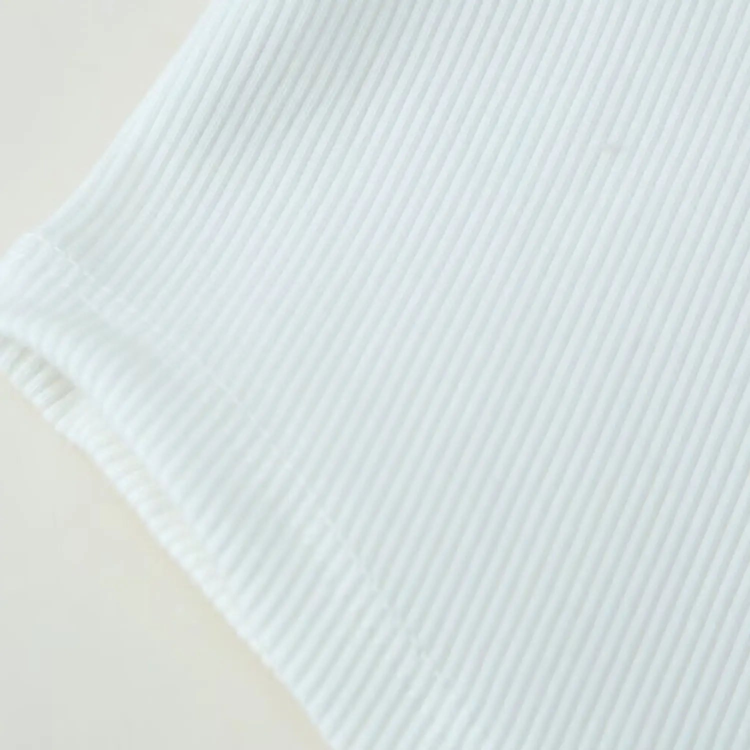 Bottom hem close-up of asymmetrical curved shark hem on rib knit body