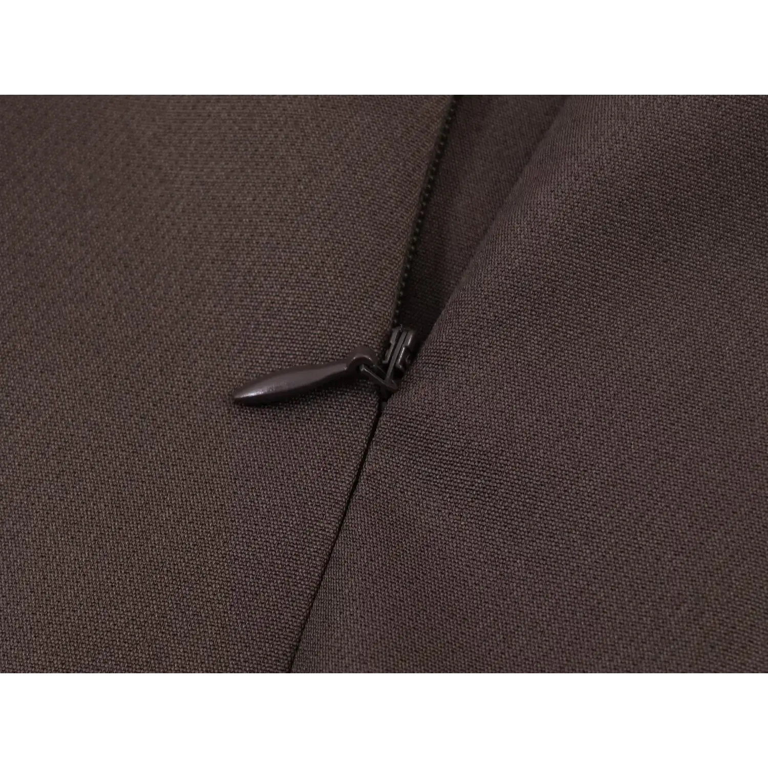 Close-up of matching dark brown coated invisible zipper, small teardrop fabric pull tab, tight side seam topstitch on suit skirt fabric