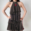Front lifestyle shot on model of dark brown sleeveless halter neck tiered waterfall ruffle mini dress, crinkled casual summer outfit