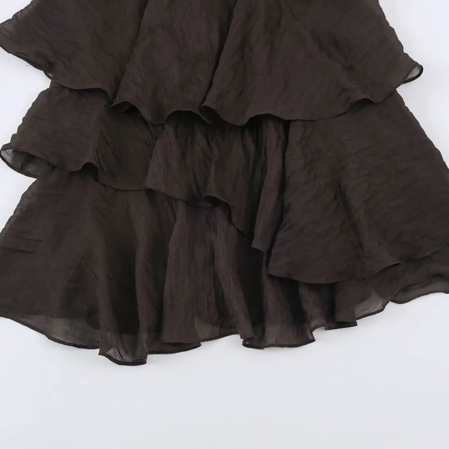 Tiered uneven ruffle skirt close-up, multi-layer asymmetrical frill hem, wrinkled brown fabric drape detail