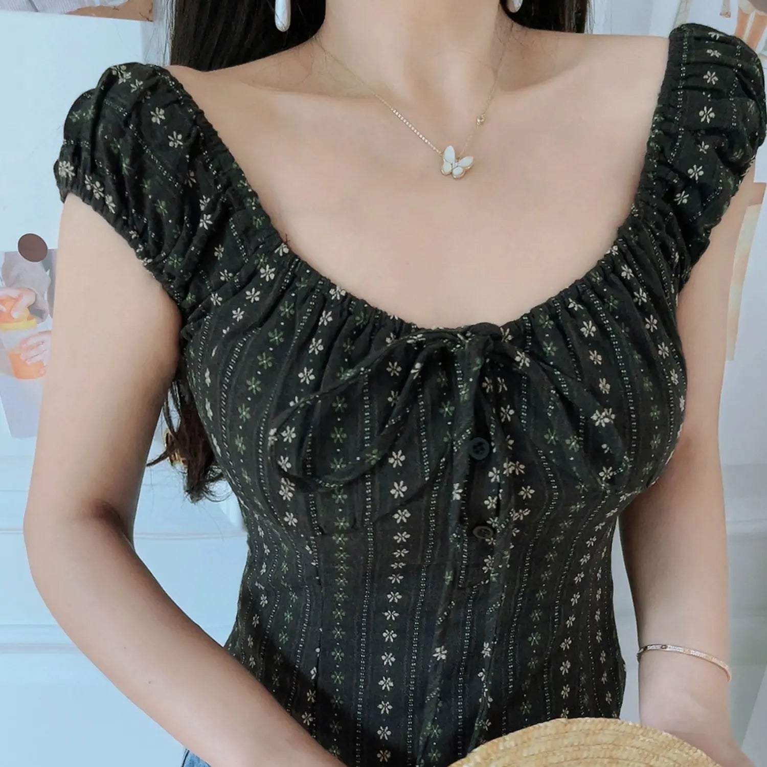 Dark brown tiny vertical floral crop top bust close-up, half open front buttons and ruched front tie model wearing shot
