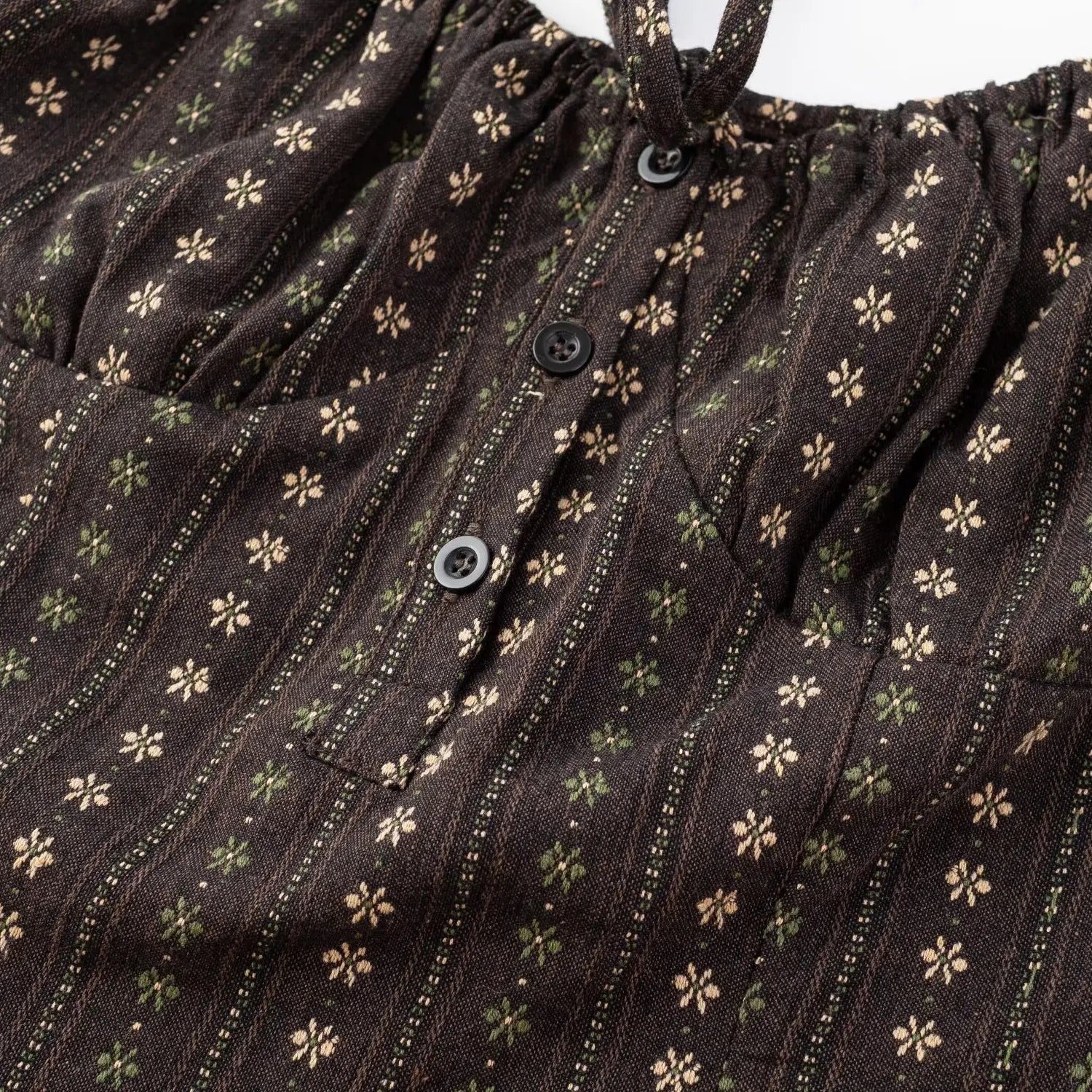 Women dark brown vertical tiny floral top bust close-up, half open black round buttons and front tie ruched woven fabric flat lay detail