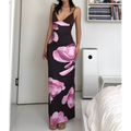Medium full indoor bedroom lifestyle shot of V-neck stretch slip maxi dress, model resting one hand on hip to highlight ruched waist fit, soft gradient pink magnolia floral print all over dark brown fabric