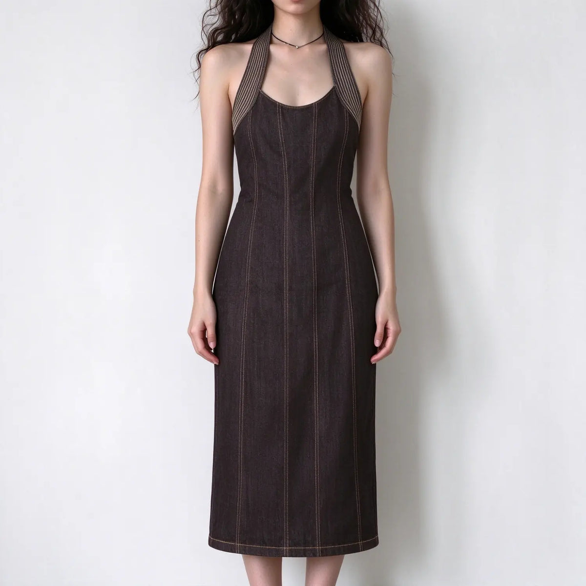 Model wearing dark denim halter maxi dress with contrast stitching and fitted bodycon silhouette, white background