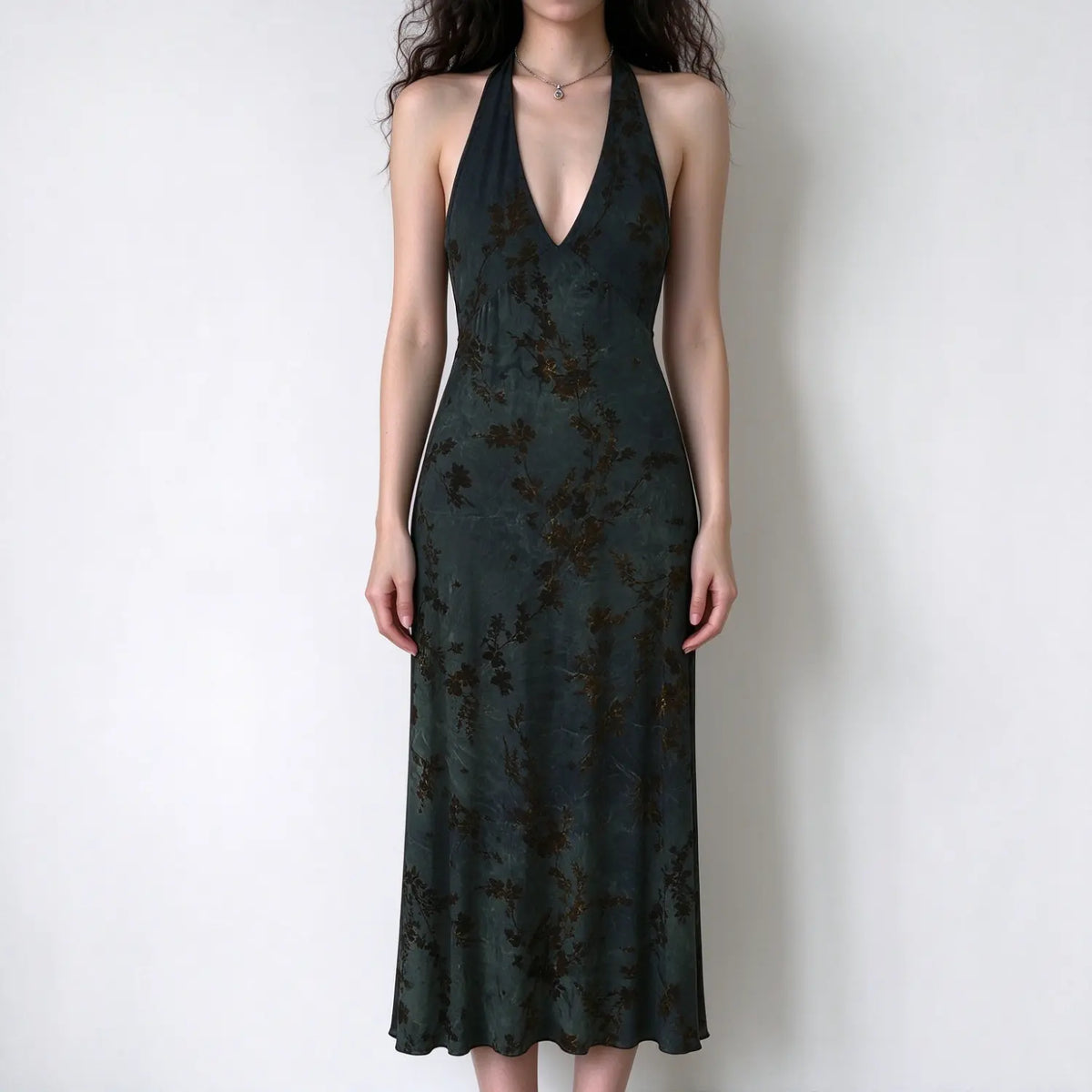 Model wearing dark green floral halter maxi dress, deep v neck, slim jersey fabric, brown floral print, white background