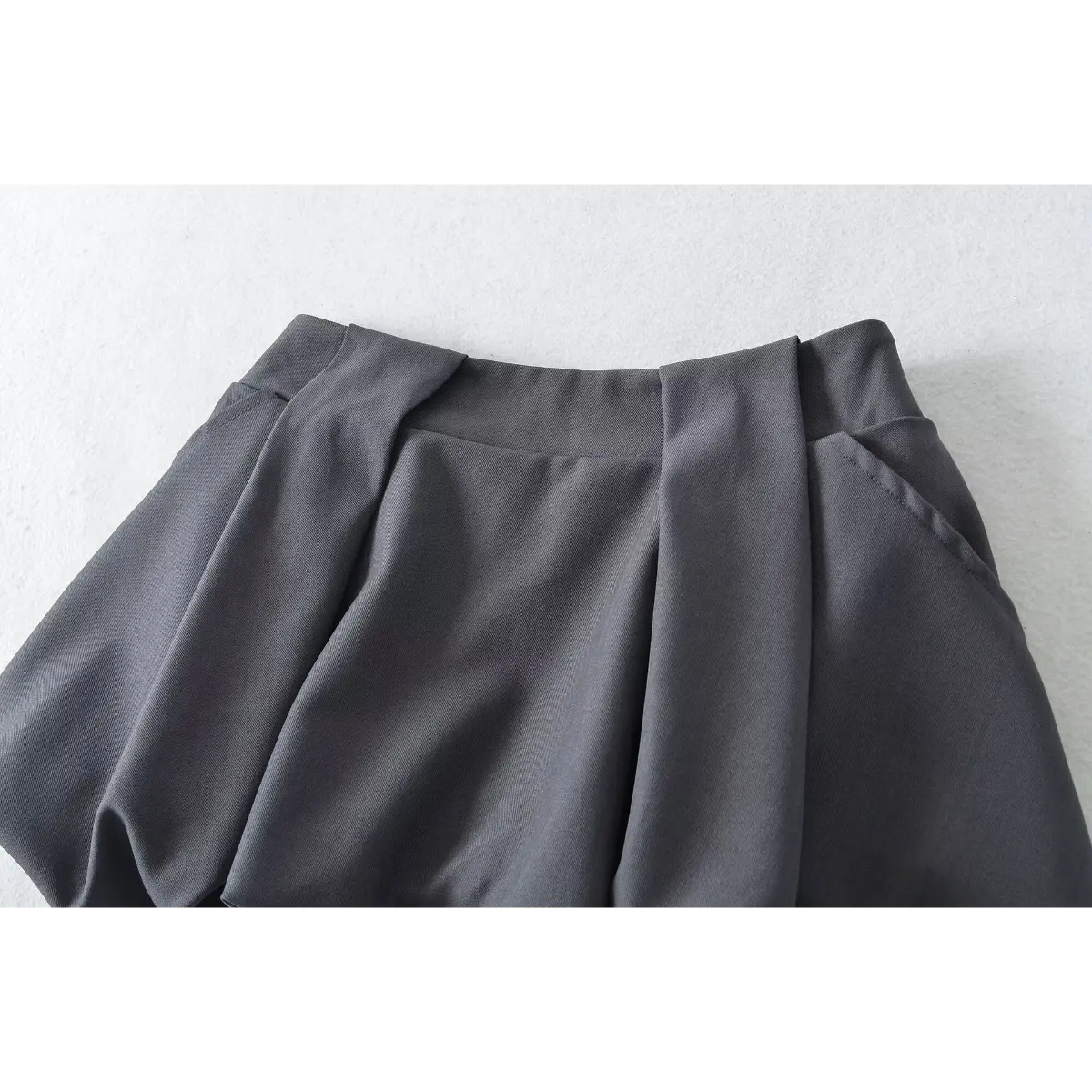 Close-up of the elasticated waistband and pleated detailing on the dark grey bubble skirt