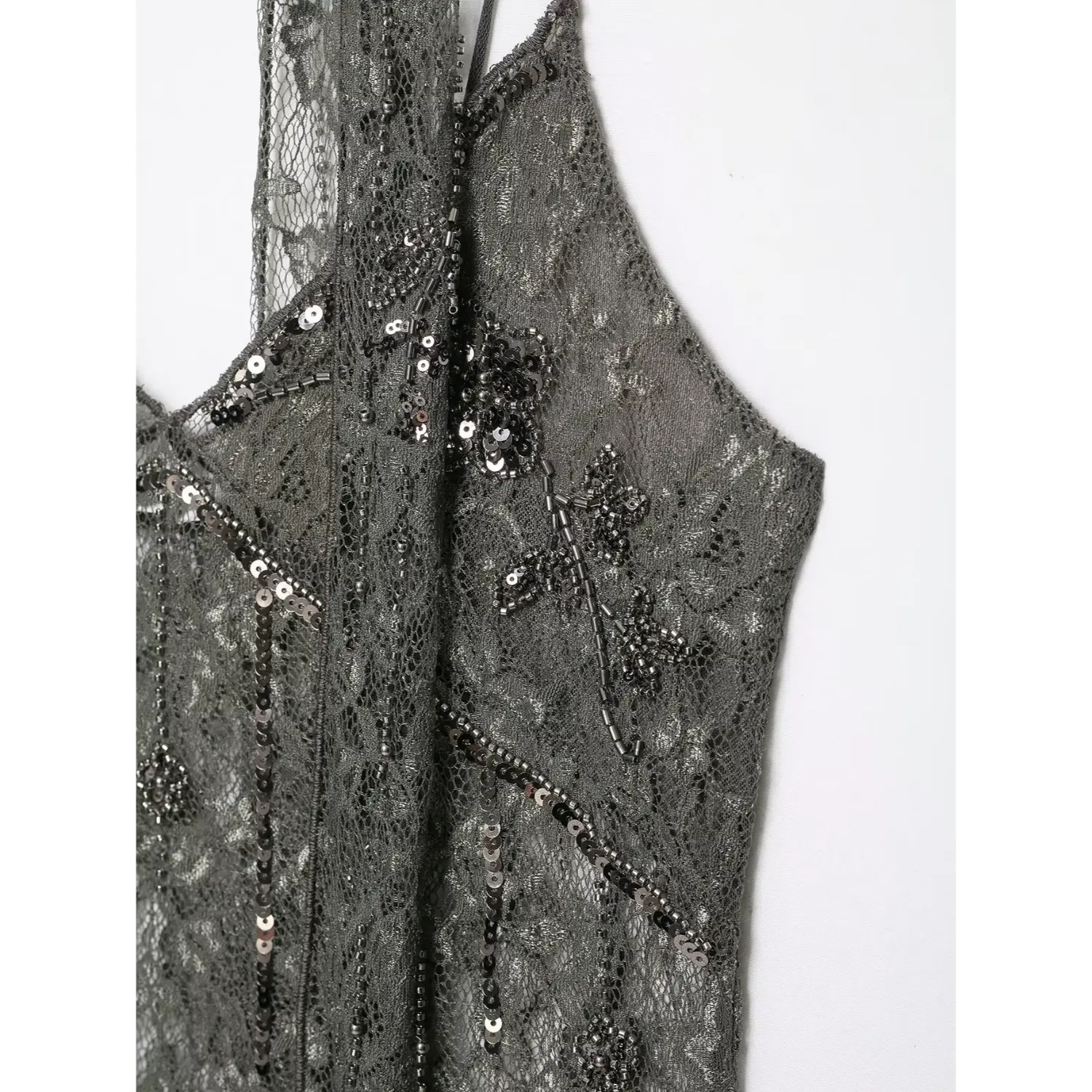 Close‑up side bust area showcasing hand‑sewn flower sequin and tube bead embroidery on dark grey lace fabric