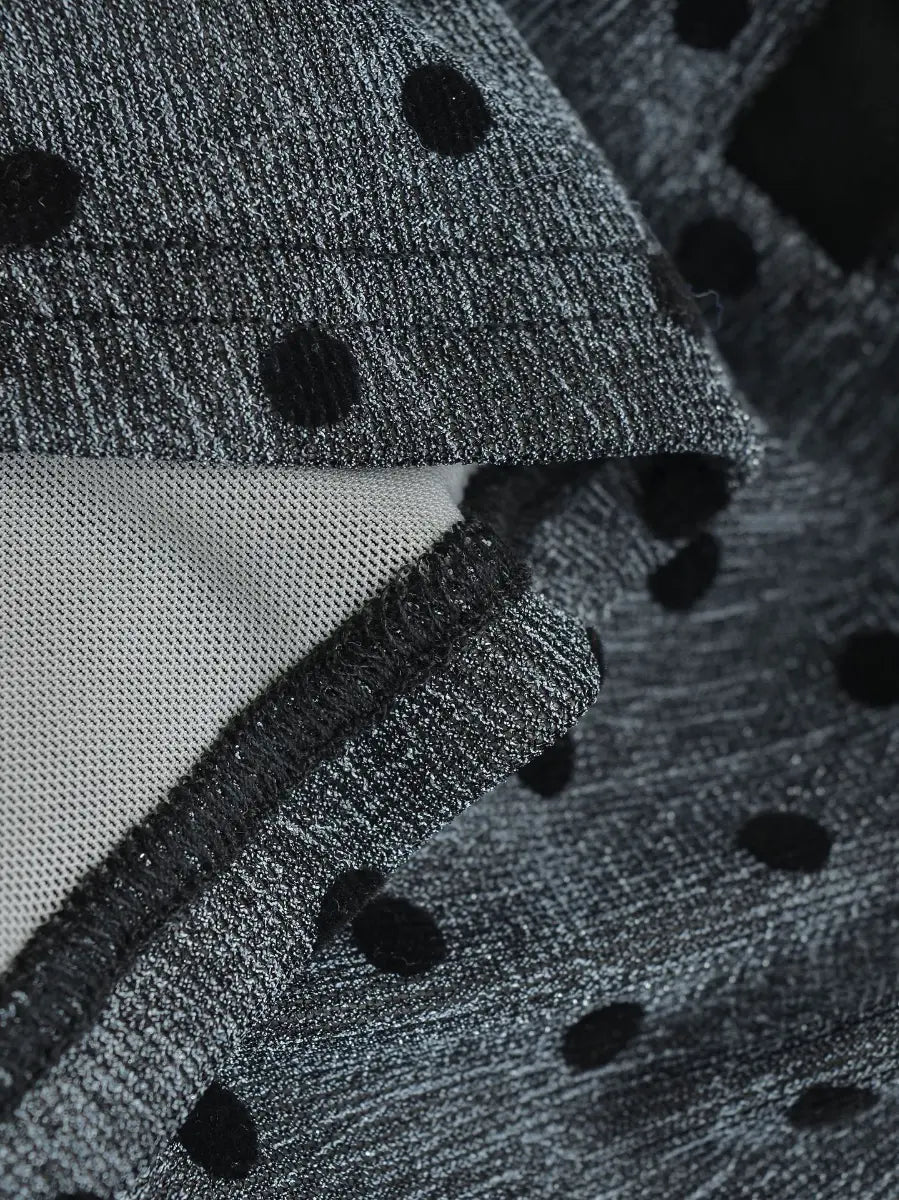 Close-up of the dark grey polka dot fabric texture, mesh lining, and finished seam on the top