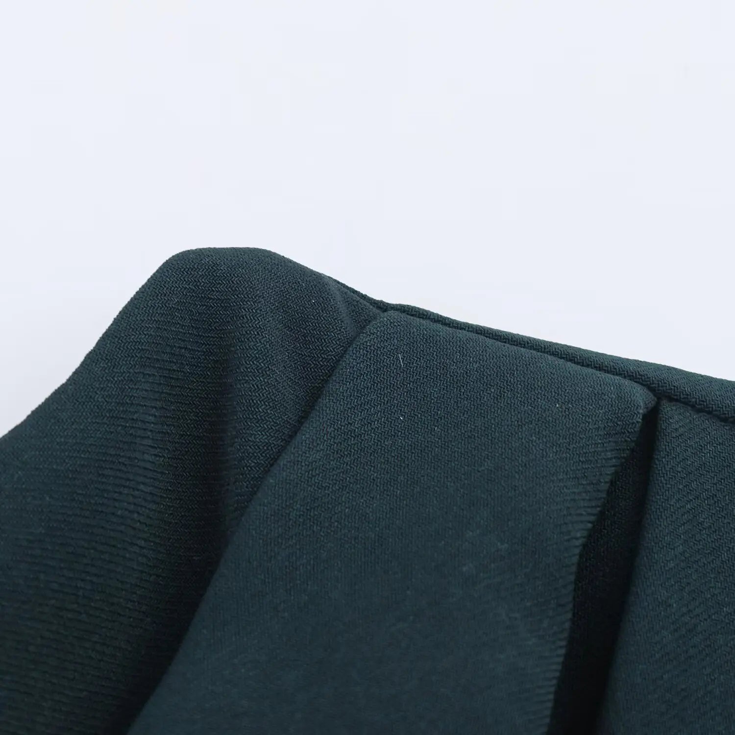 Extreme close‑up of fabric folds, herringbone woven texture of dark teal dress material