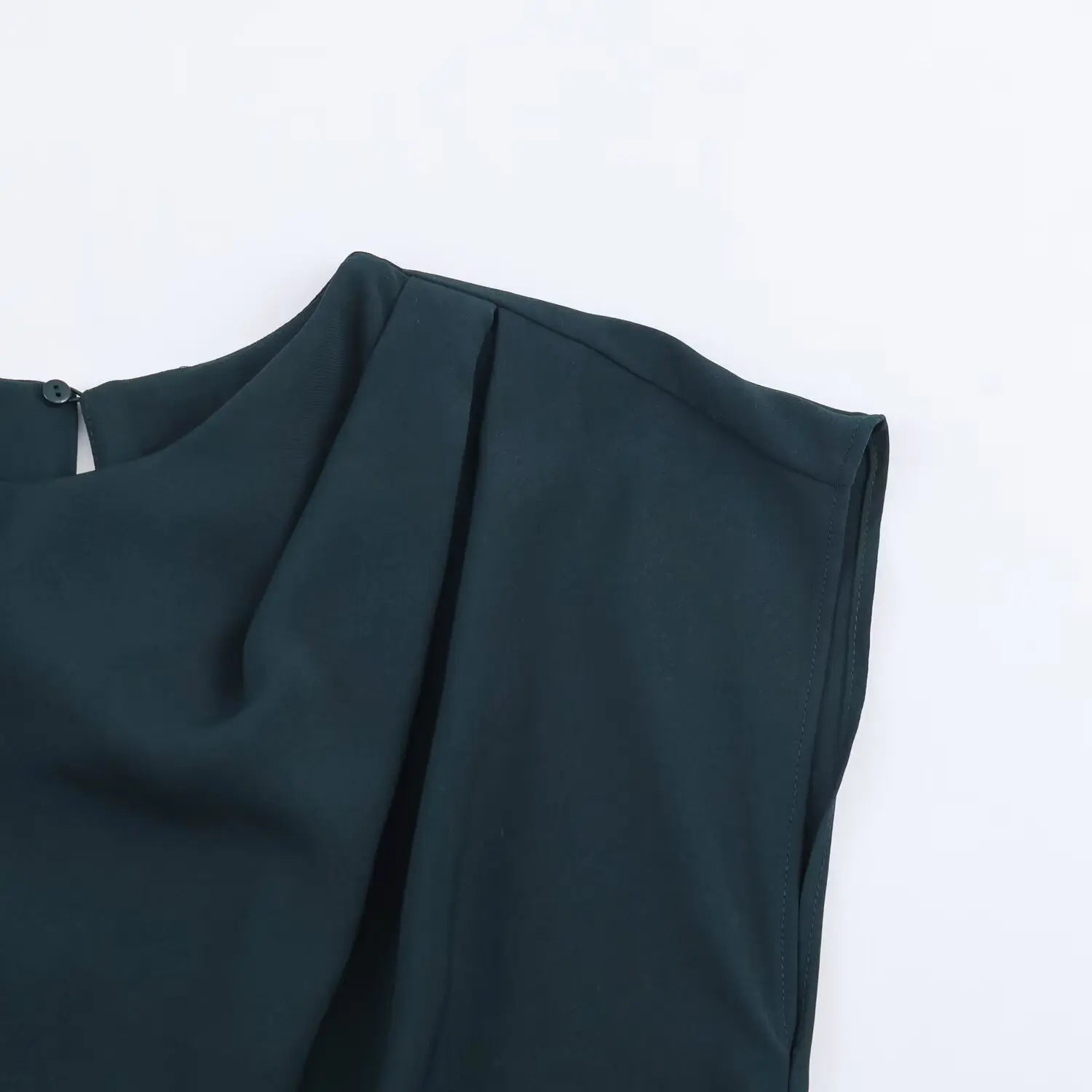 Partial close‑up of shoulder and draped pleat detail, tailored cap sleeve, fine stitching on dark teal fabric