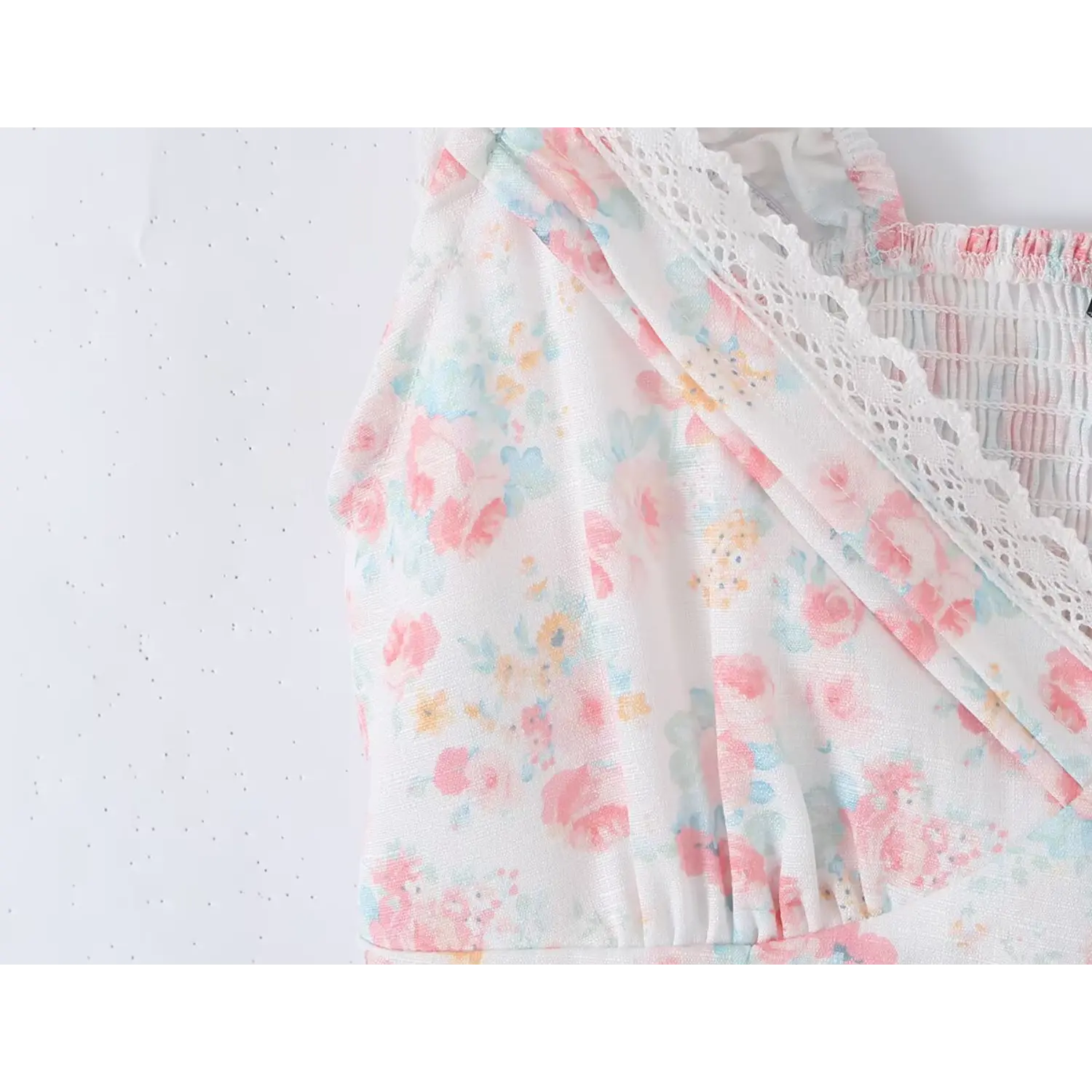 Bust partial shot deep V neck cropped camisole, layered scalloped hollow lace overlay wrap front, fabric covered vertical button placket, elastic ruffle lace-trim cap sleeves, soft pastel watercolor ditsy floral woven fabric