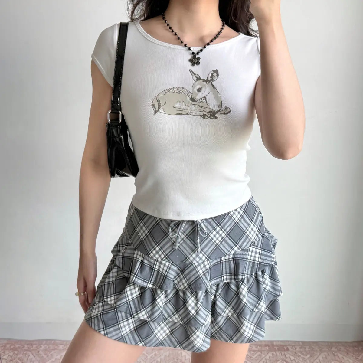 The complete outfit featuring the deer print t-shirt, plaid skirt, and black shoulder bag.