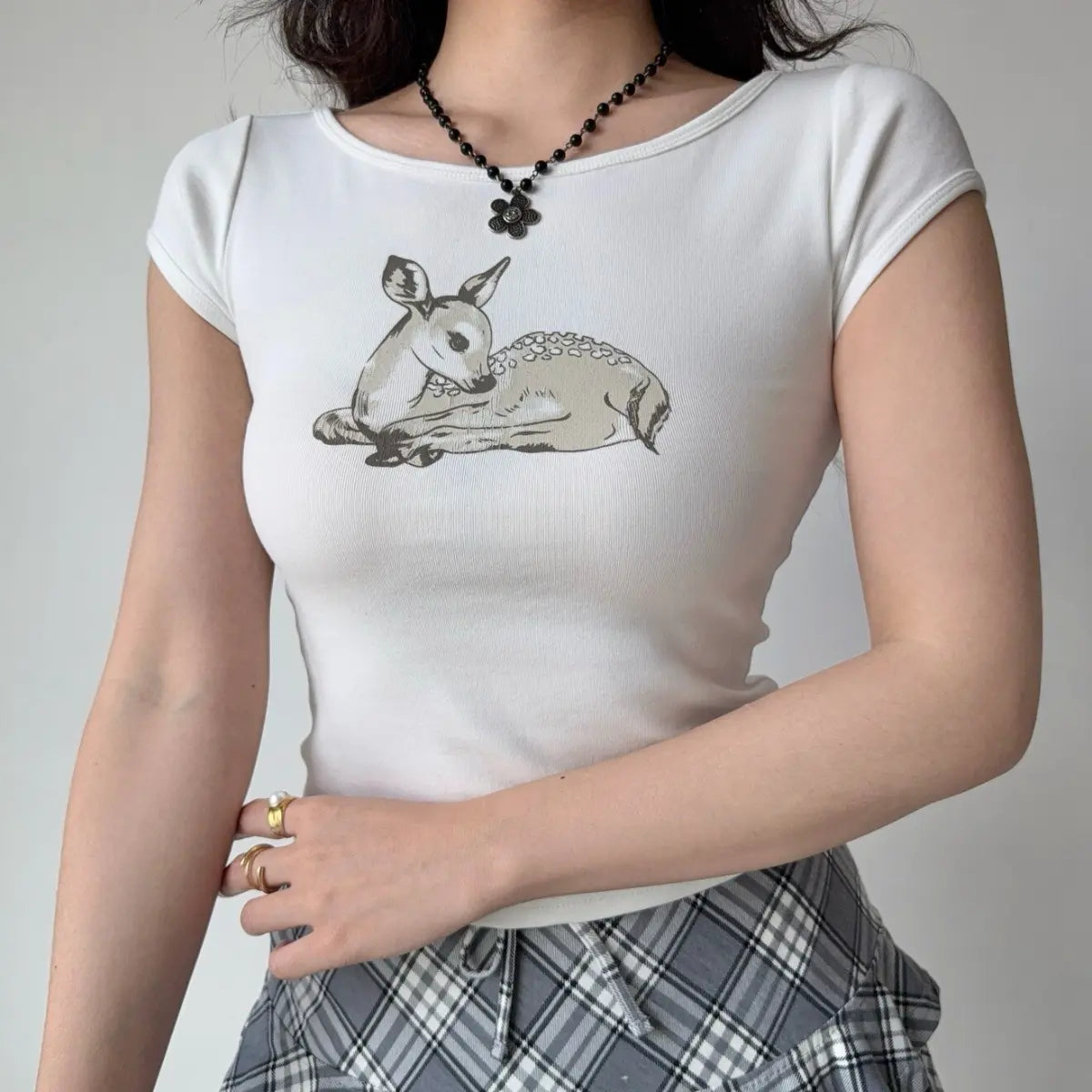 The white deer print t-shirt styled with rings, highlighting the graphic print.