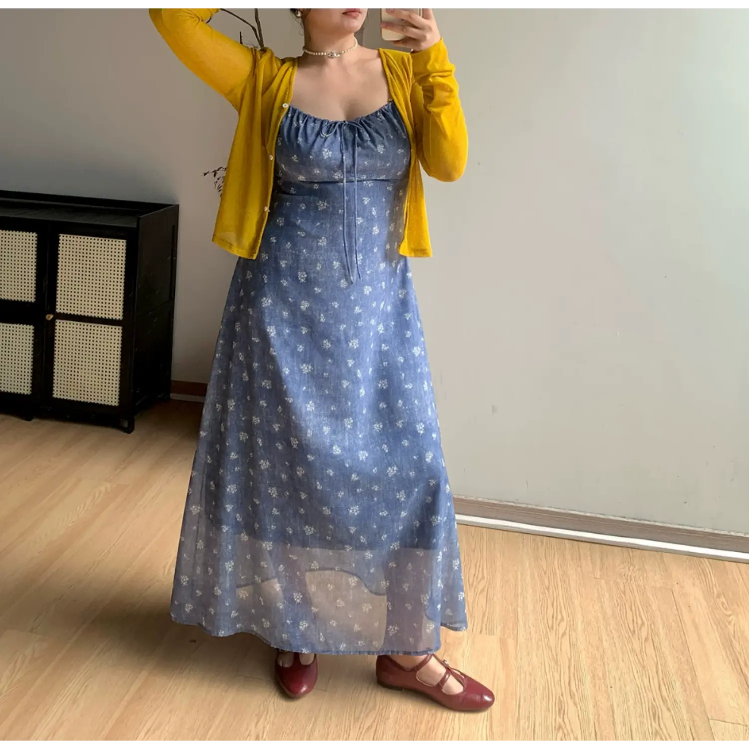 Full body indoor mirror shot of faded blue tiny white floral maxi dress, layered slim bright yellow long sleeve cropped knit cardigan, matching burgundy mary jane flat shoes