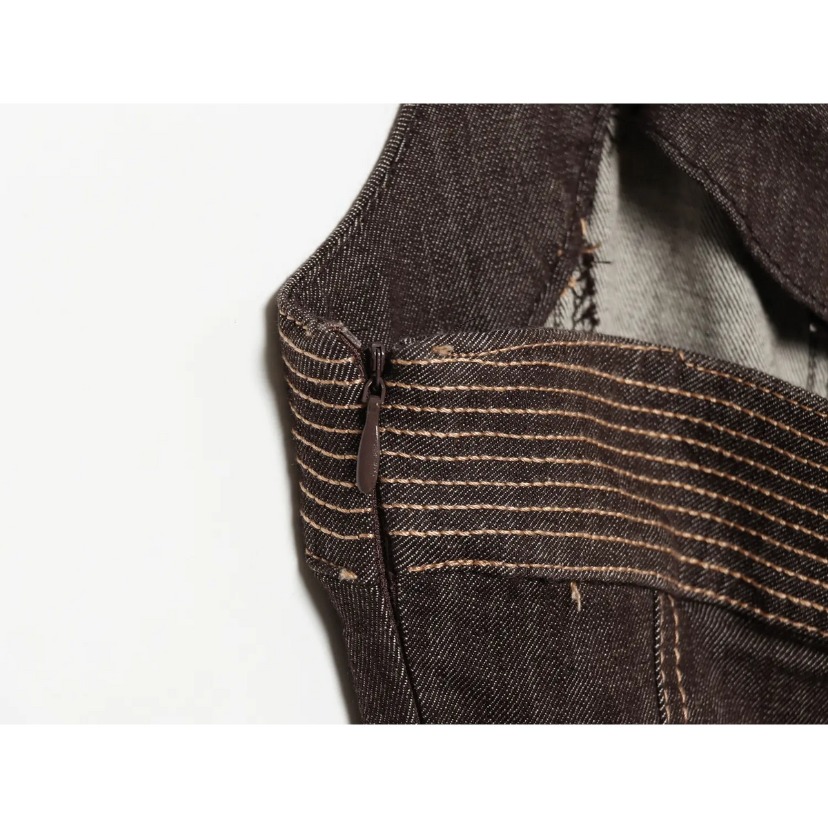 Close‑up of invisible side zipper with contrast stitching on dark brown halter denim dress