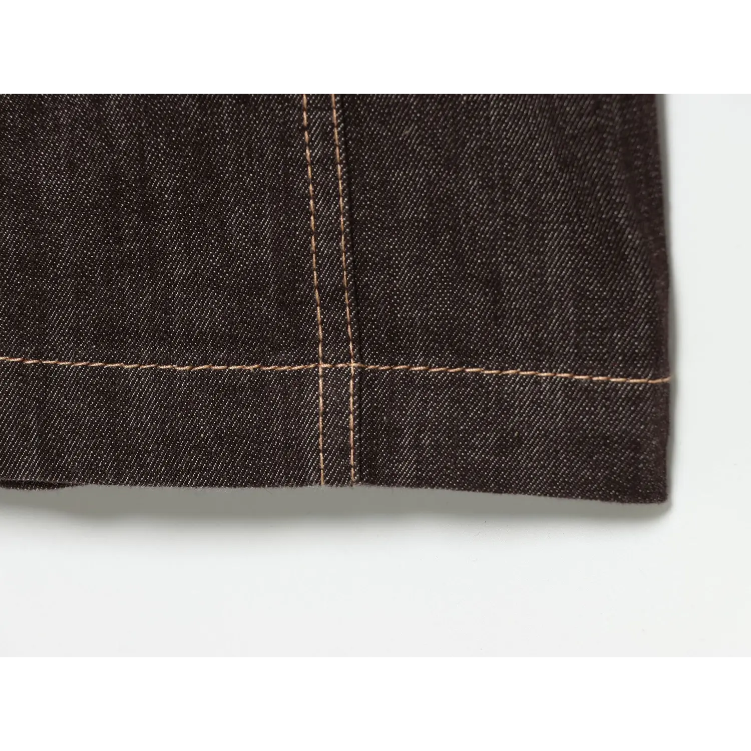 Macro close‑up of dress hem, neat contrast topstitching on dark brown denim fabric