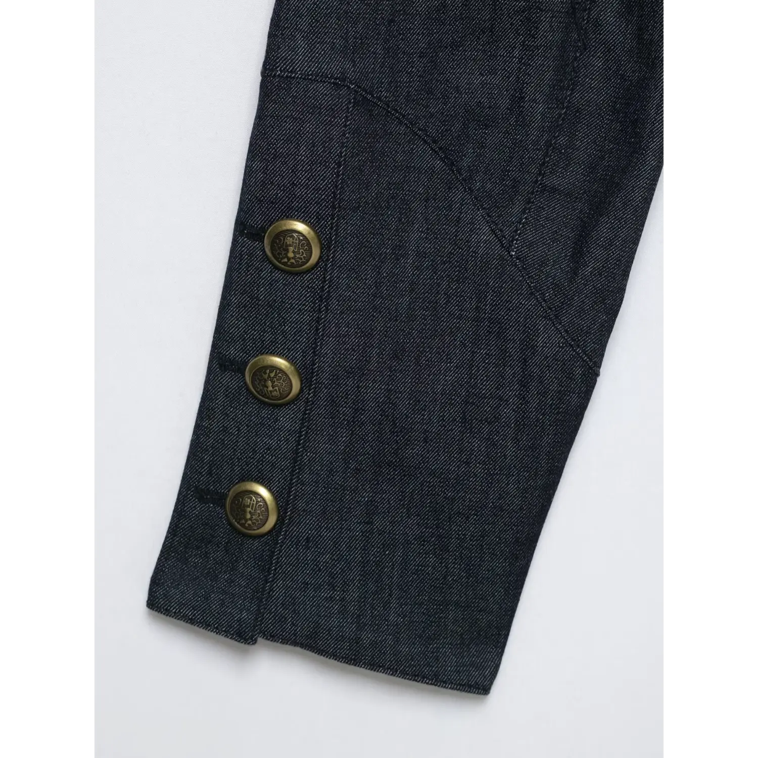Closeup sleeve cuff three antique brass buttons dark denim jacket