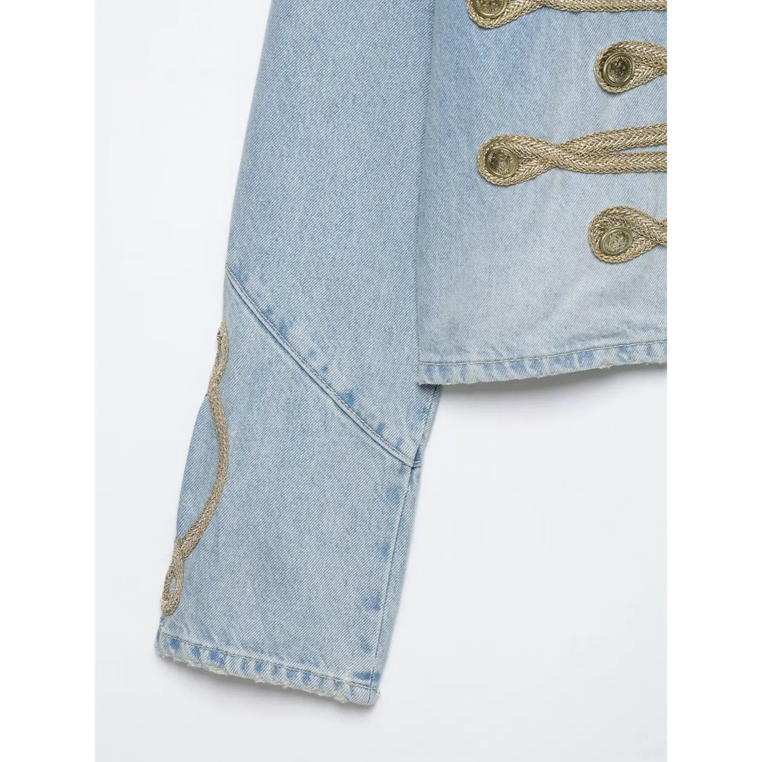 Close-up sleeve detail with woven gold rope embroidery on cropped military denim jacket