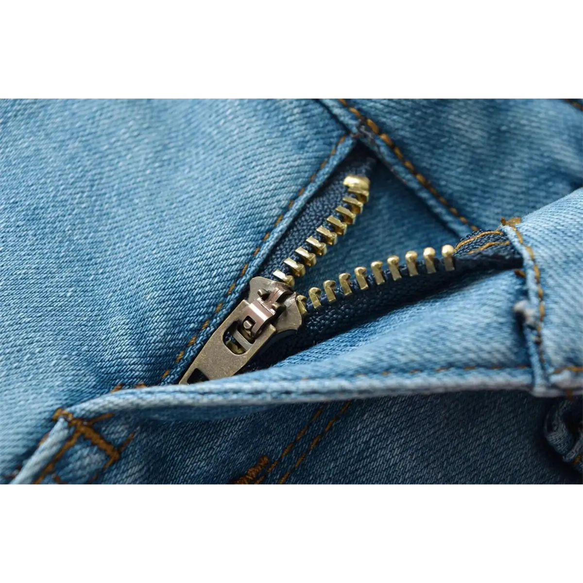 Close-up of the brass zipper on light blue low-rise denim shorts.