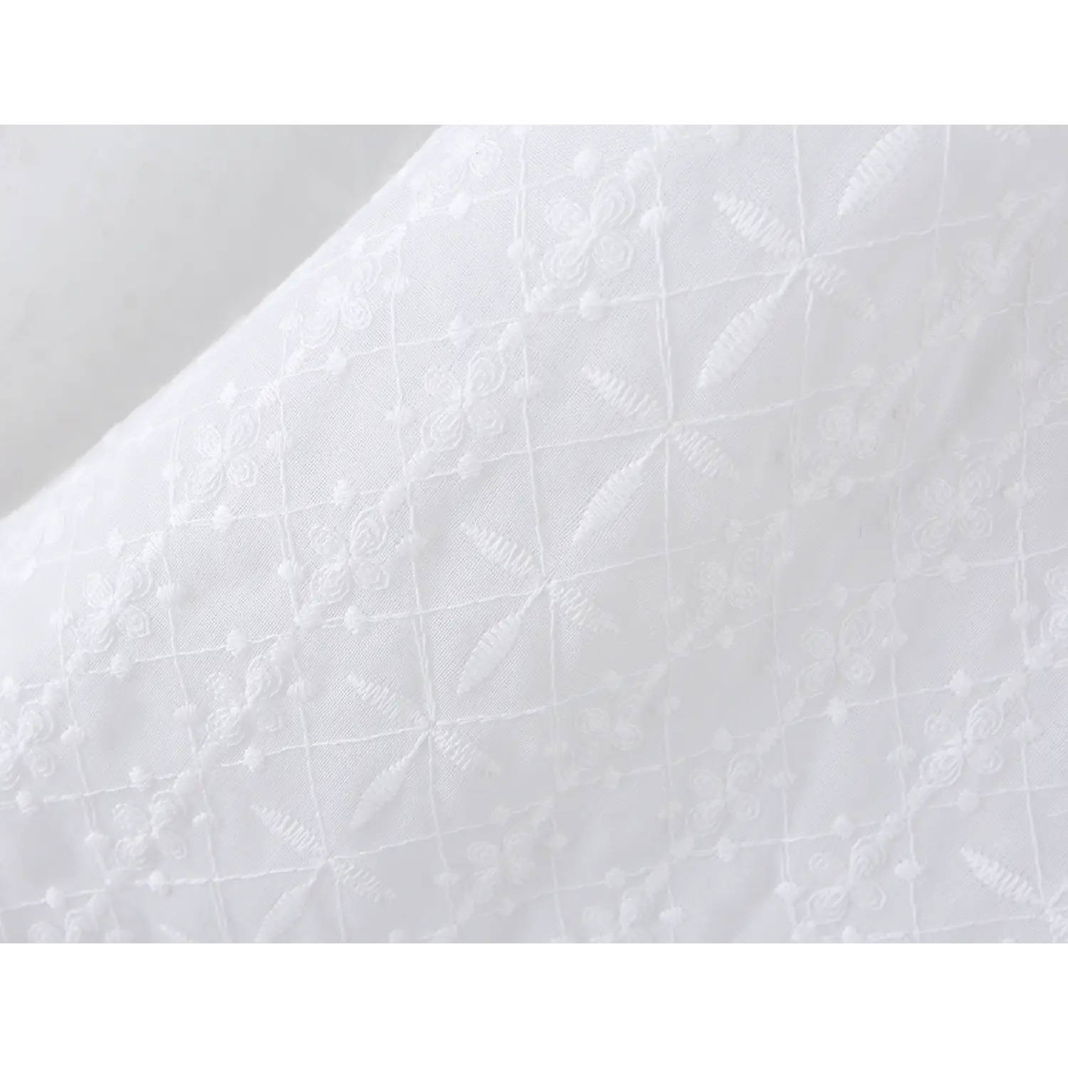 All-over diamond four-leaf floral 3D eyelet embroidery fabric macro flat close-up, raised stitch texture lightweight breathable spring summer mini dress cloth shot