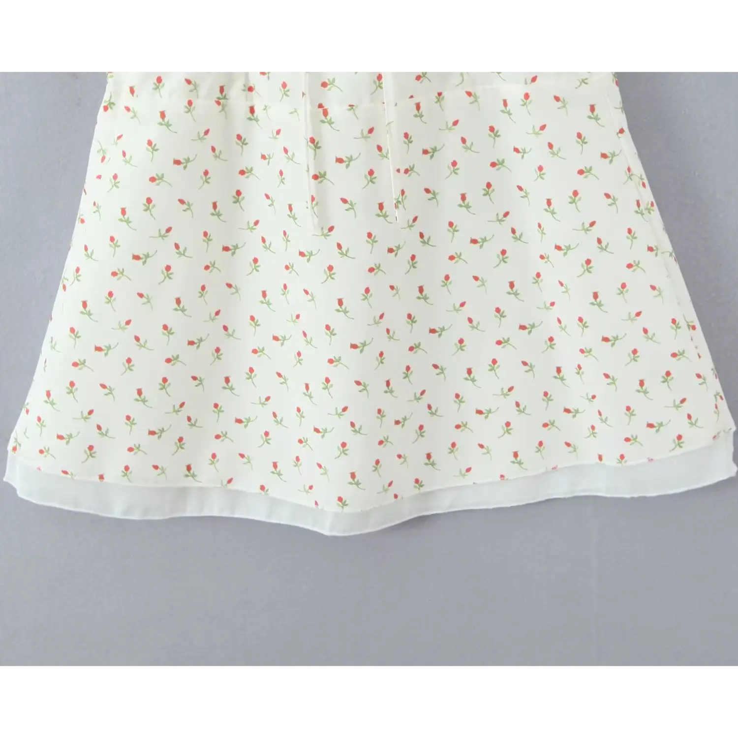 Partial full shot a‑line skirt bottom hem ditsy rose print cami dress finished outer hem grey wall background