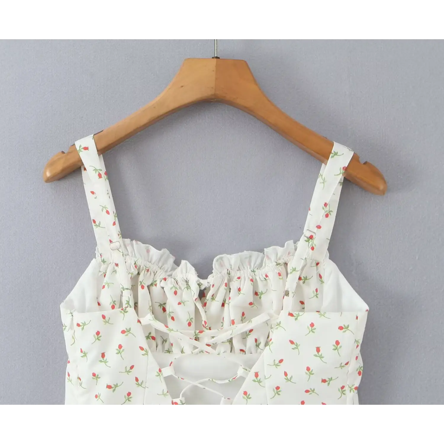 Close‑up back shoulder area adjustable metal slider straps ruffled back neckline white ditsy rose print cami dress on wooden hanger