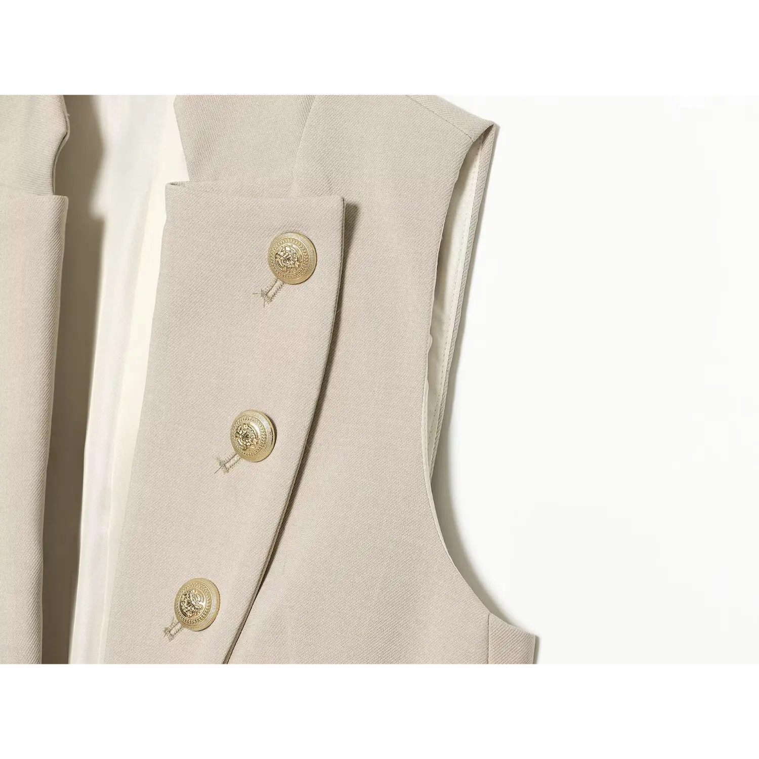 Side view double‑breasted button placket of beige sleeveless blazer