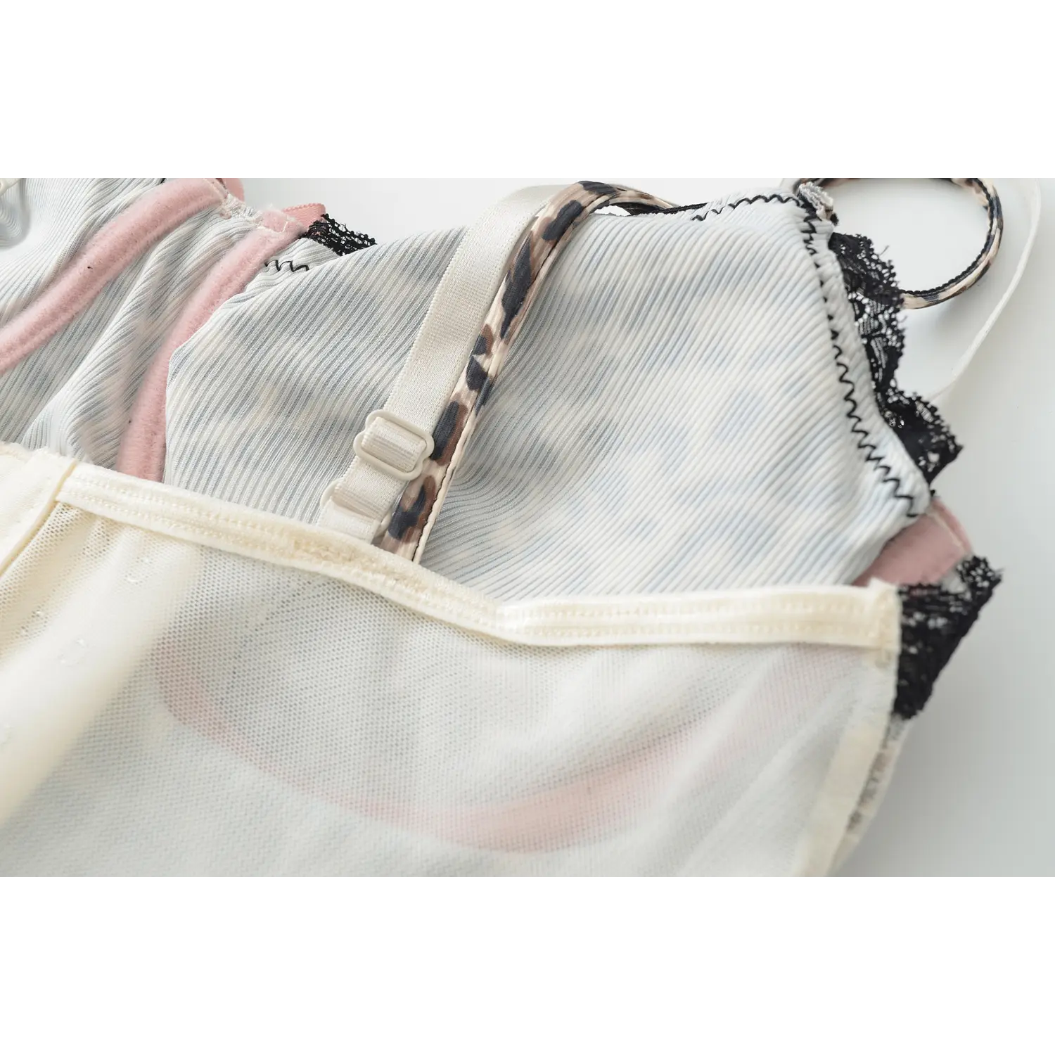 Double layer leopard print strap corset tank macro flat close-up, outer white inner leopard adjustable buckle thin straps, scalloped black lace v-neck edge mesh fabric white background shot