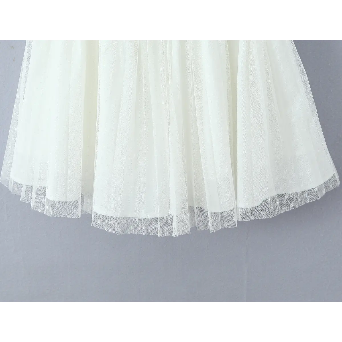 Hem close of dual-layer dotted mesh skirt, outer sheer tulle + solid underdress with neat finished edge stitching.