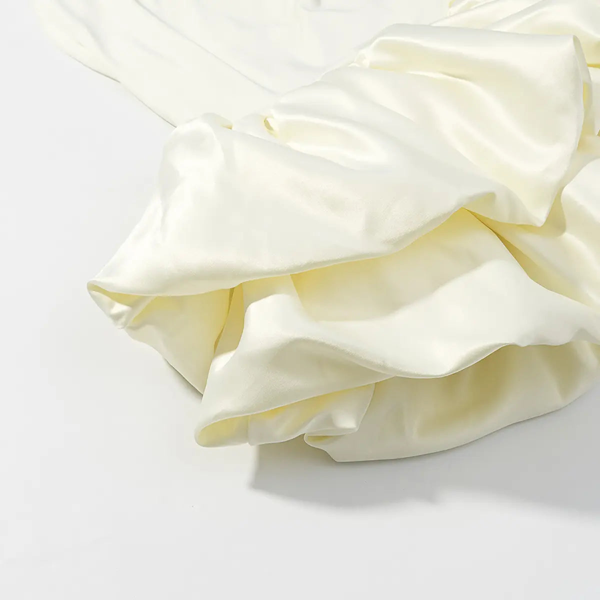 Close-up of the double-layered ruffle hem on a cream halter dress, highlighting the voluminous, tiered design.