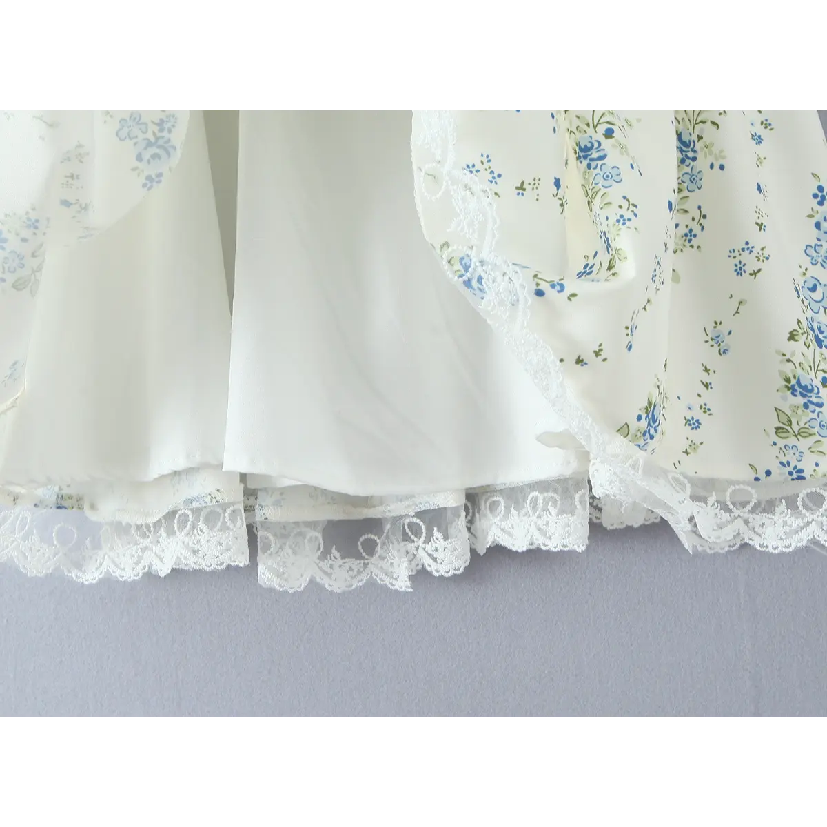 Close-up of the double-layered skirt and lace hem on a cream floral dress, showing the lining and scalloped lace.