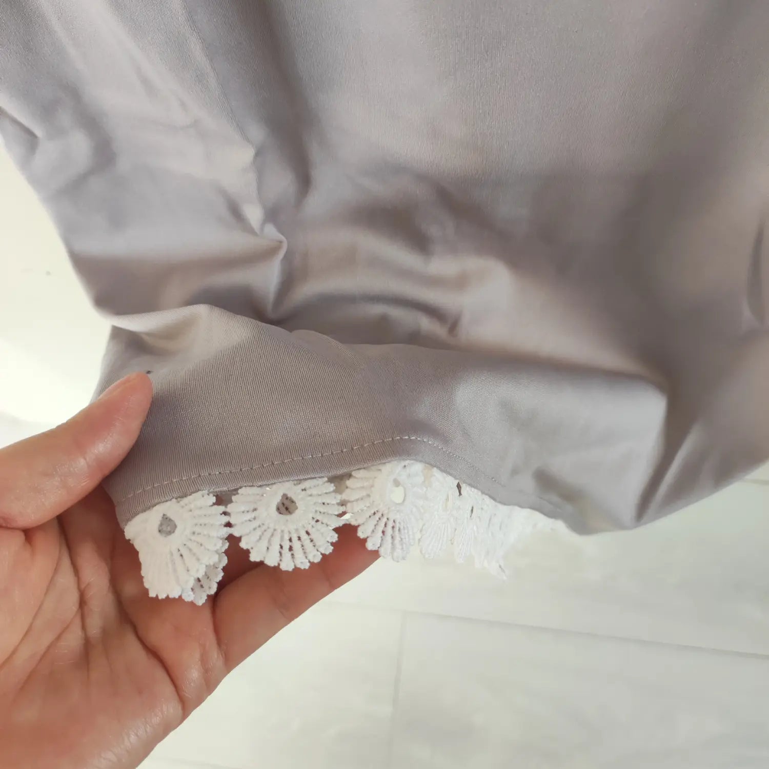 Close‑up bottom hem white floral lace trimming of grey bodycon midi dress