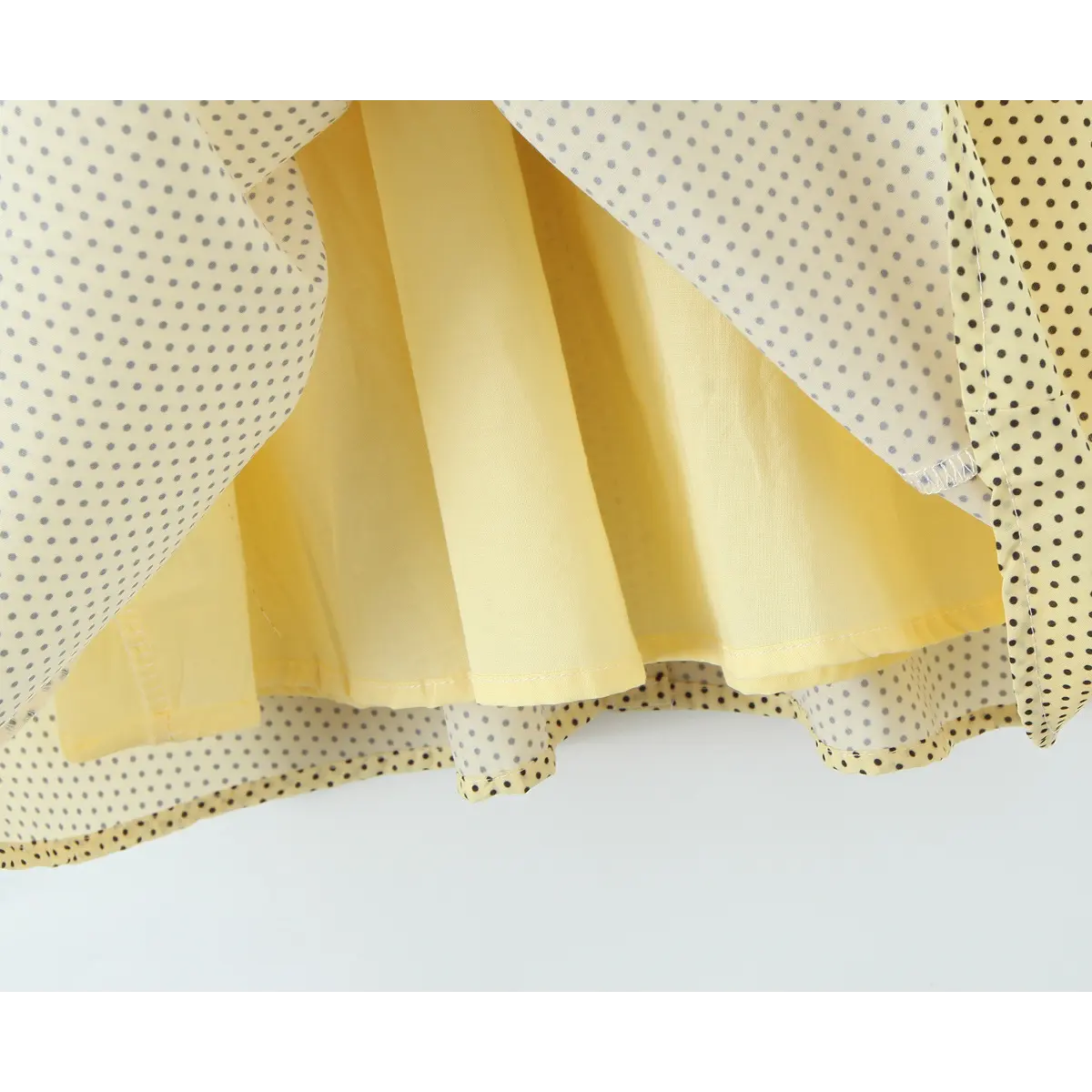 Inner solid yellow lining under outer polka dot skirt hem