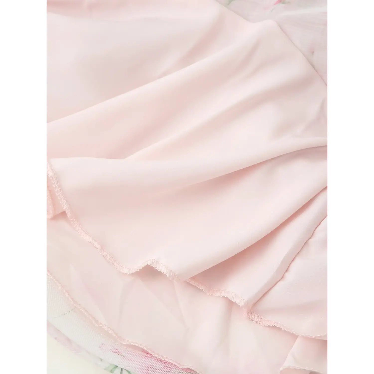 Skirt hem lining partial shot, solid light pink smooth inner lining, neat serged stitching, outer sheer chiffon overlay
