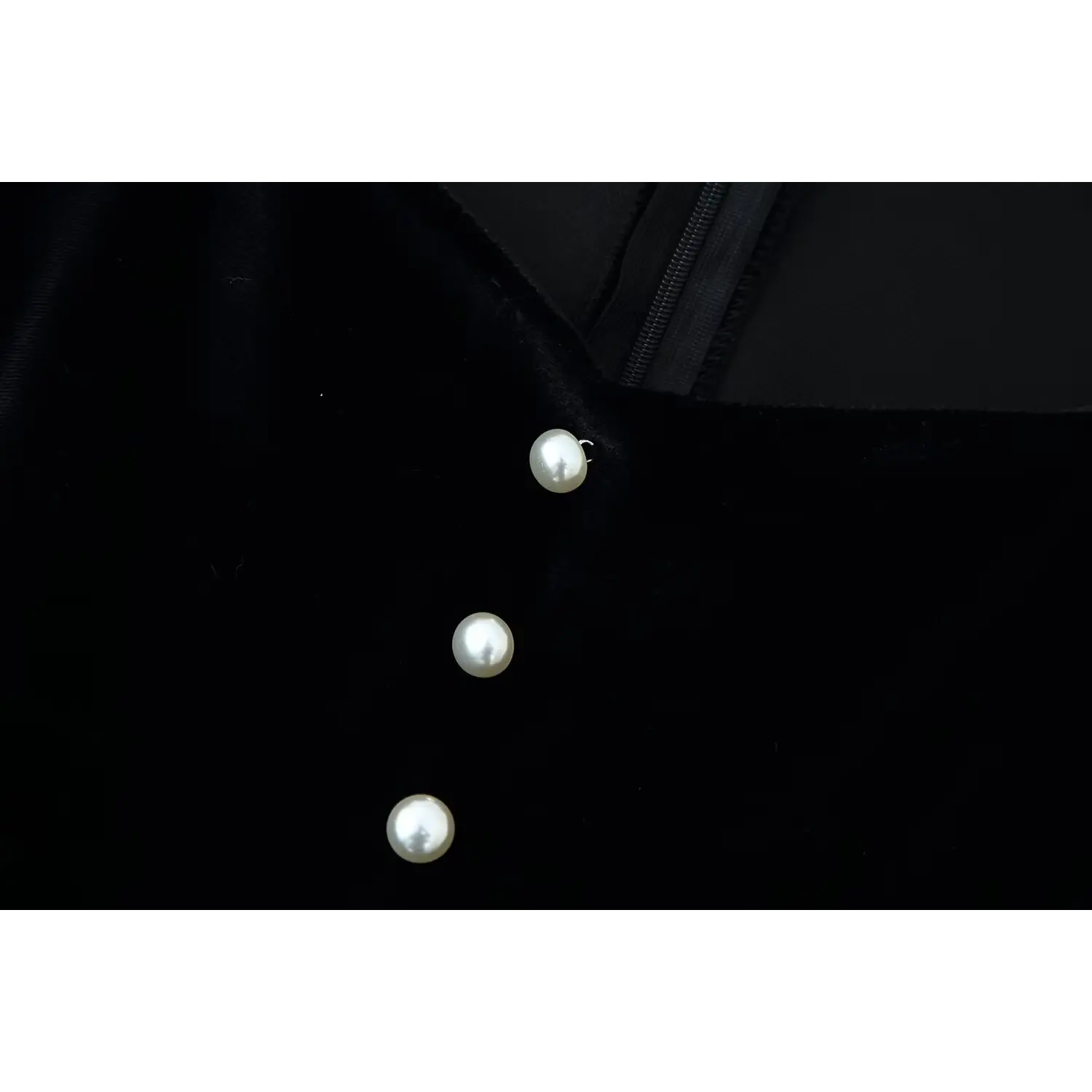 Macro close‑up of round pearl decorative buttons on black velvet bodice