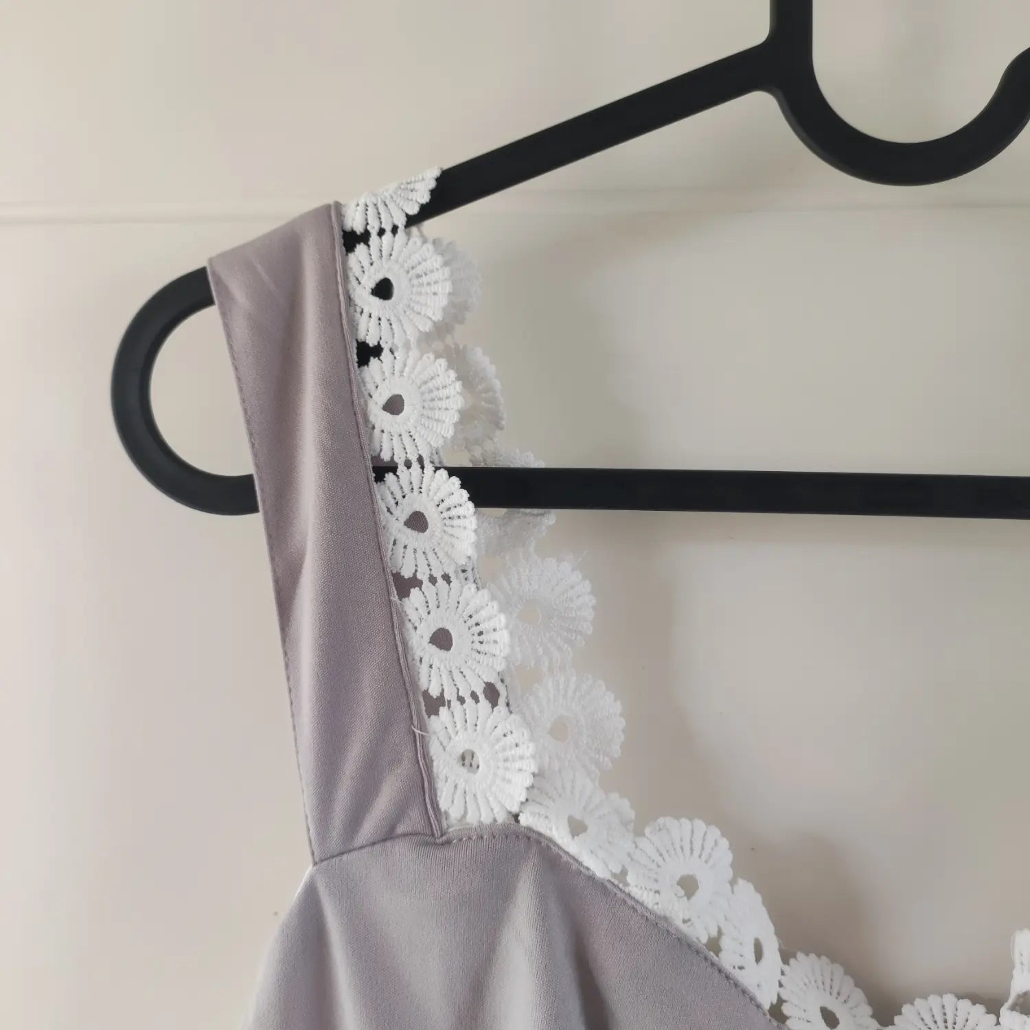 Close‑up of shoulder strap and neckline white floral lace trim on grey midi dress