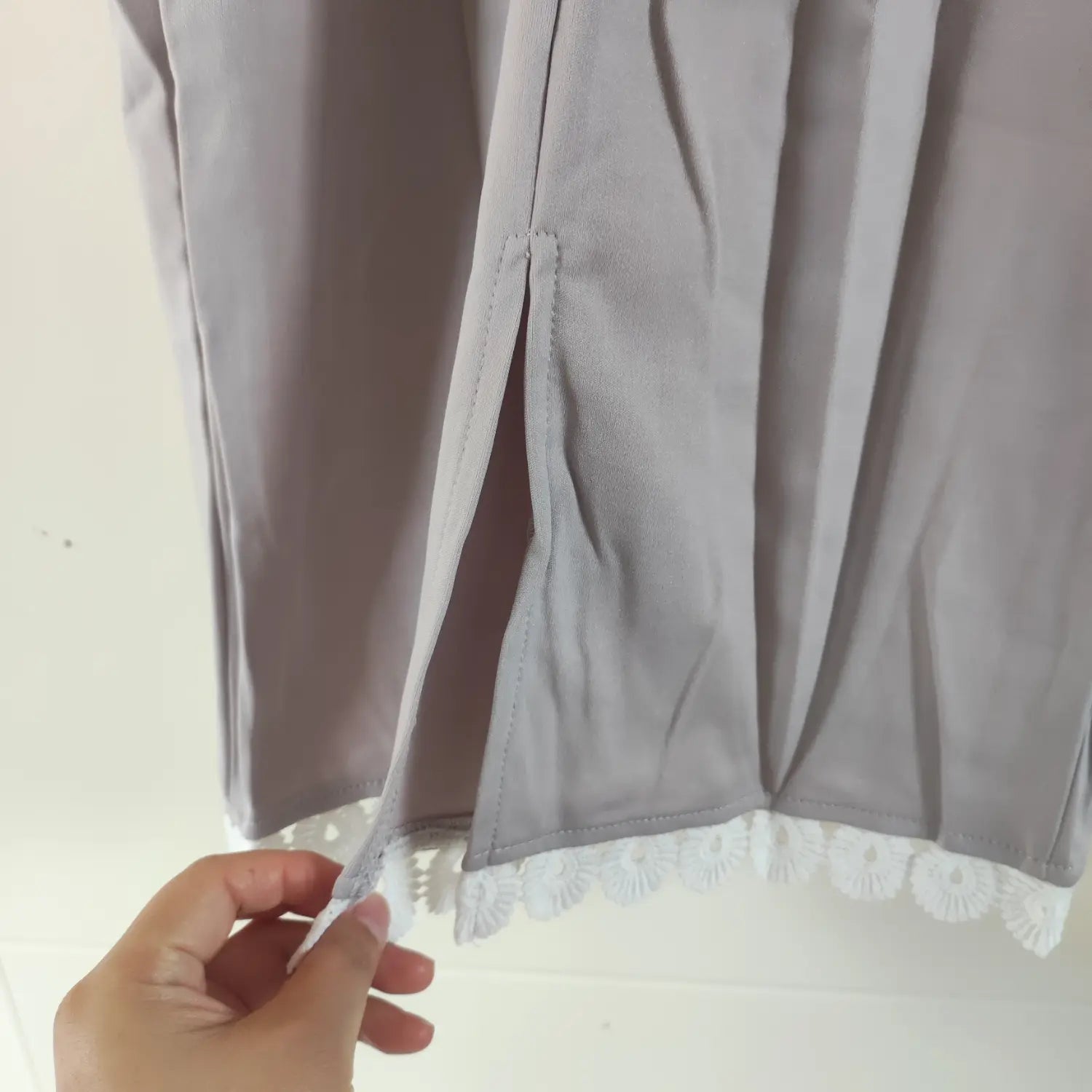 Close‑up side slit and hem lace detail on grey bodycon midi dress