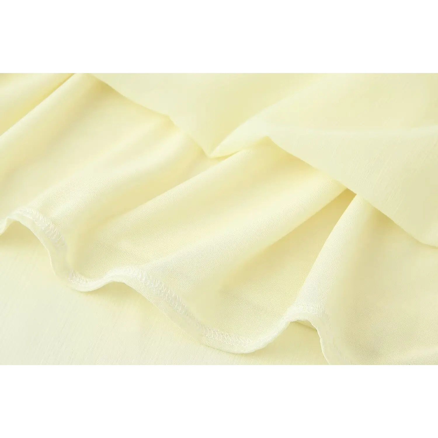 Interior close-up neat serged overlock stitching on pale yellow maxi dress hem, smooth solid matching lining attached to outer crinkle chiffon